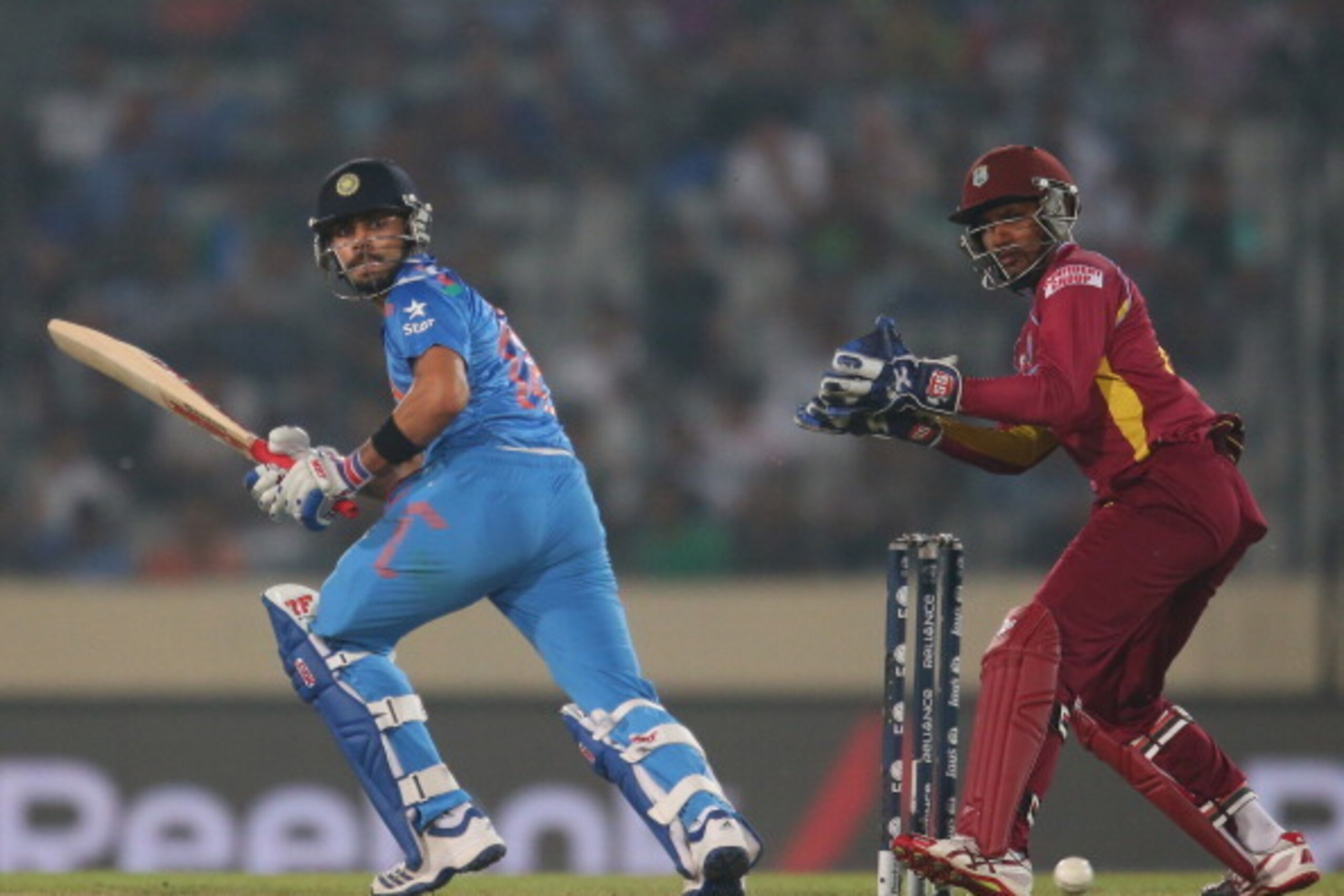 DHAKA, BANGLADESH - MARCH 23:  Virat Kohli of India bats as Denesh Ramdin of the West Indies looks on during the ICC World Twenty20 Bangladesh 2014 match between the West Indies and India at Sher-e-Bangla Mirpur Stadium on March 23, 2014 in Dhaka, Banglad
