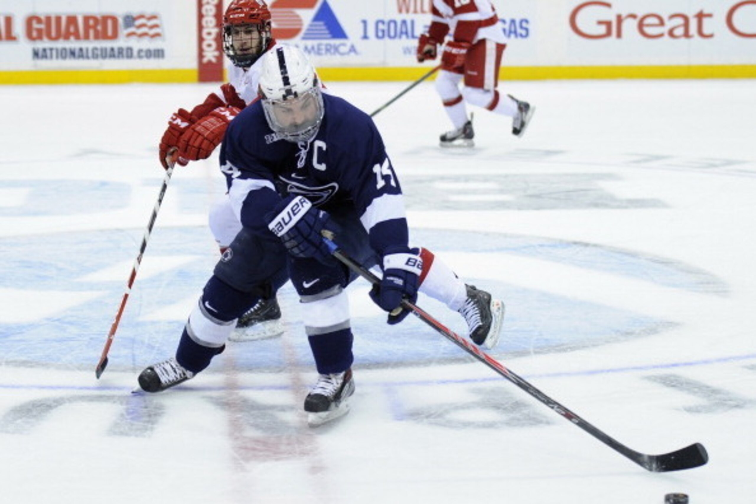 ST PAUL, MN - MARCH 21: Tommy Olczyk #14 of the Penn State Nittany Lions controls the puck against Kevin Schulze #28 of the Wisconsin Badgers during the first period of the semifinal game of the Big Ten Men's Ice Hockey Championship on March 21, 2014 at X