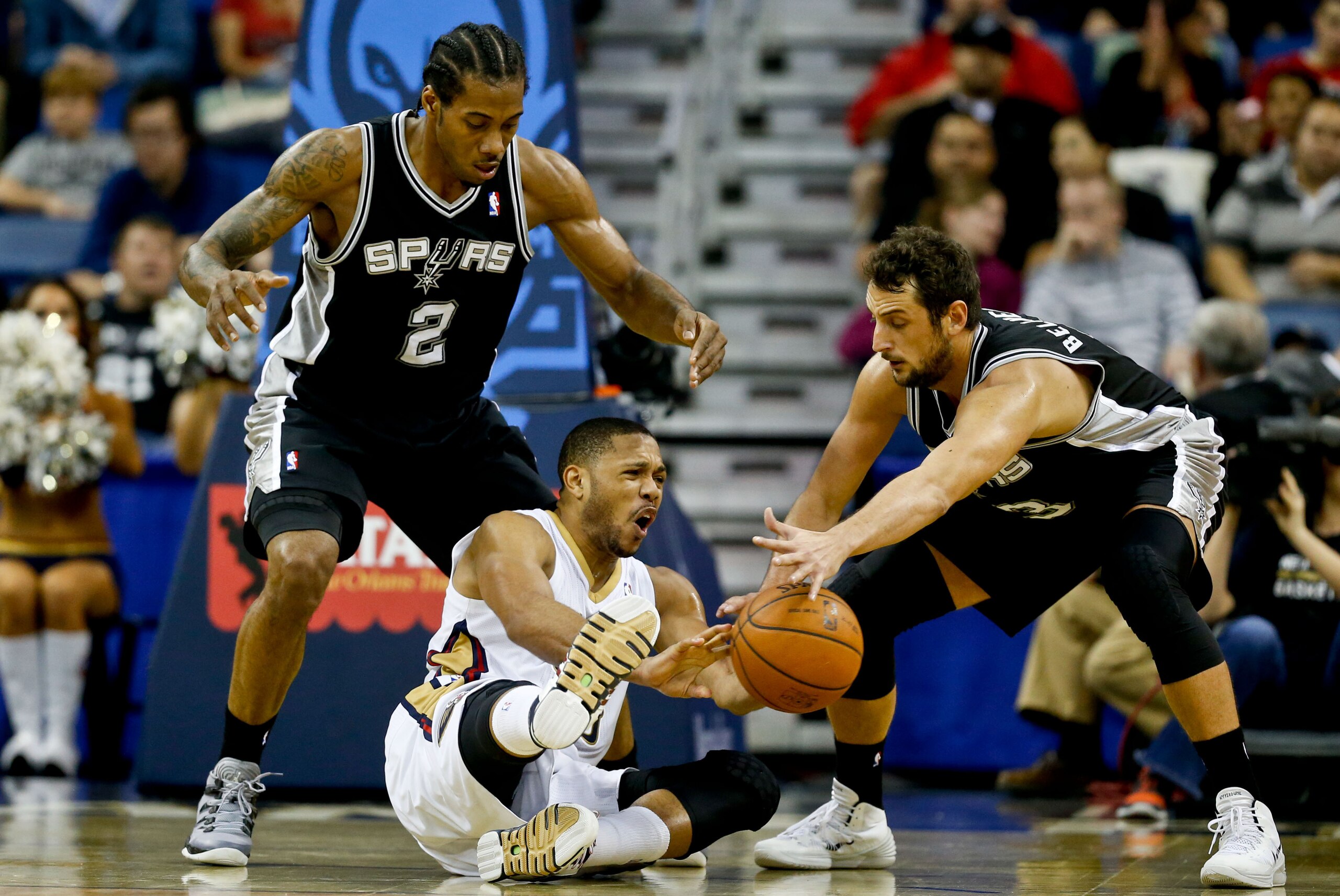 Jan 13, 2014; New Orleans, LA, USA; New Orleans Pelicans shooting guard Eric Gordon (10) passes as San Antonio Spurs shooting guard Marco Belinelli (3) and small forward Kawhi Leonard (2) pressure on defense during the second quarter of a game at the New