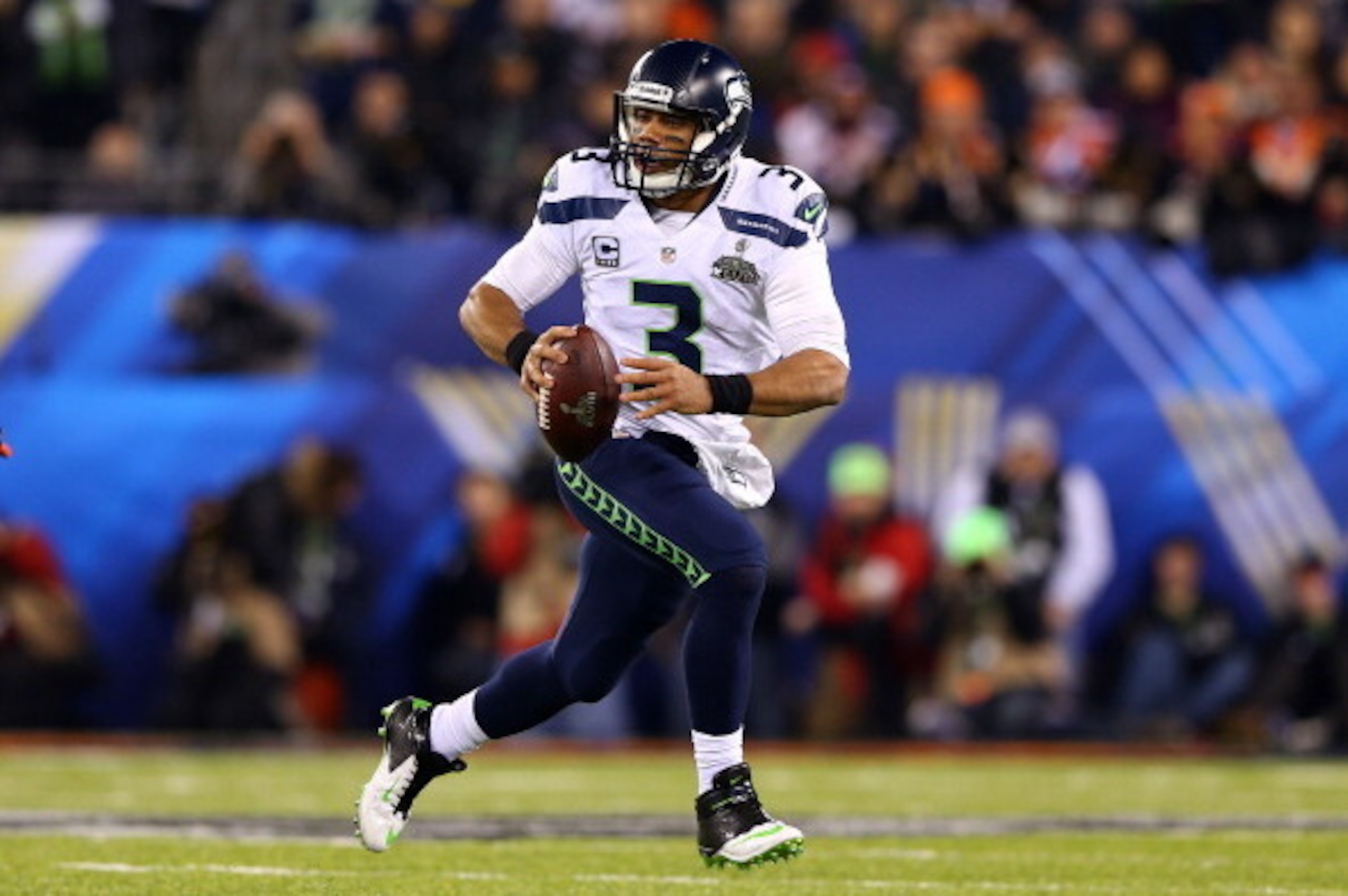 EAST RUTHERFORD, NJ - FEBRUARY 02:  Quarterback Russell Wilson #3 of the Seattle Seahawks scrambles against the Denver Broncos during Super Bowl XLVIII at MetLife Stadium on February 2, 2014 in East Rutherford, New Jersey.  (Photo by Elsa/Getty Images)