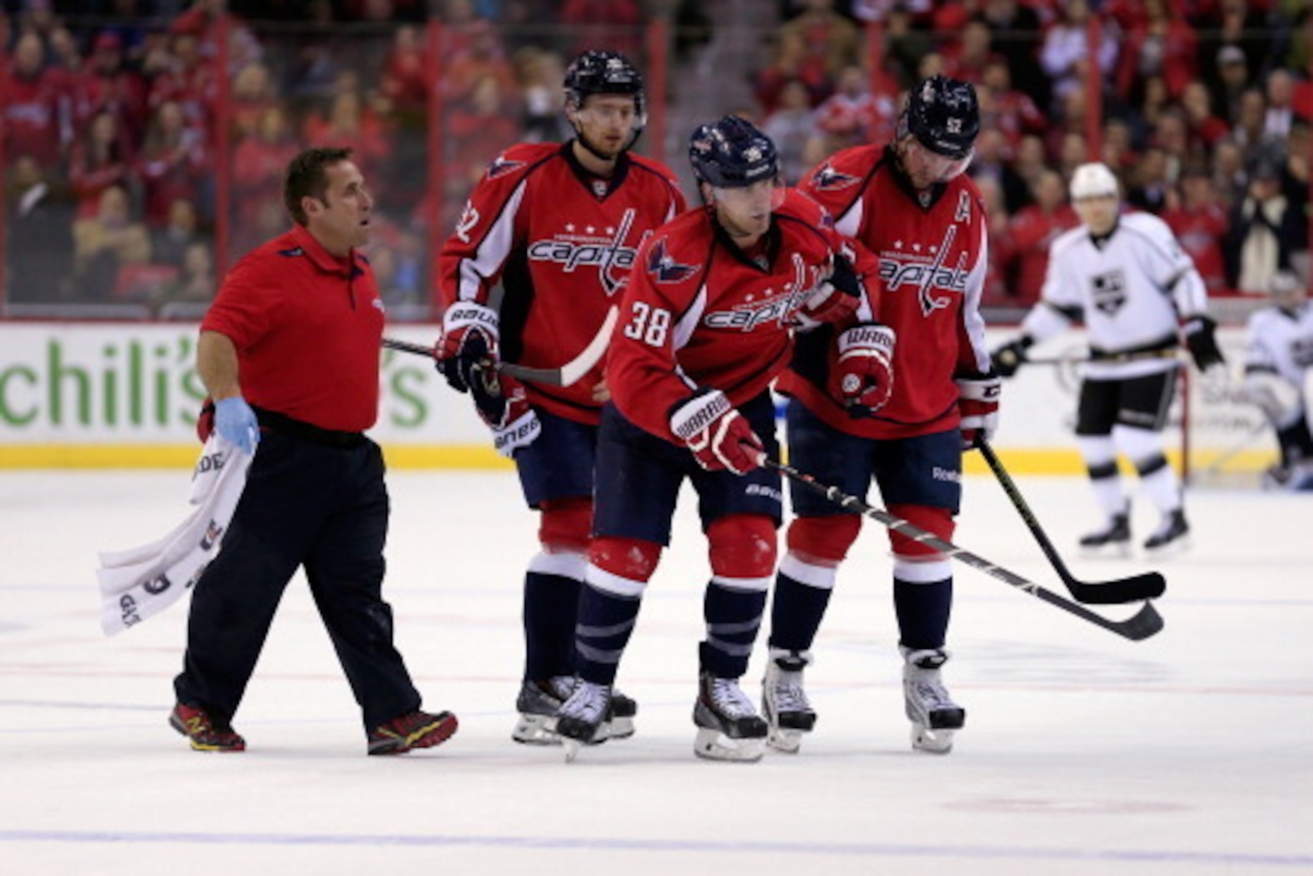 WASHINGTON, DC - MARCH 25: Jack Hillen #38 of the Washington Capitals is helped off the ice after colliding with teammate Alex Ovechkin #8 (not pictured) during the third period of the Capitals 5-4 shootout loss to the Los Angeles Kings at Verizon Center 