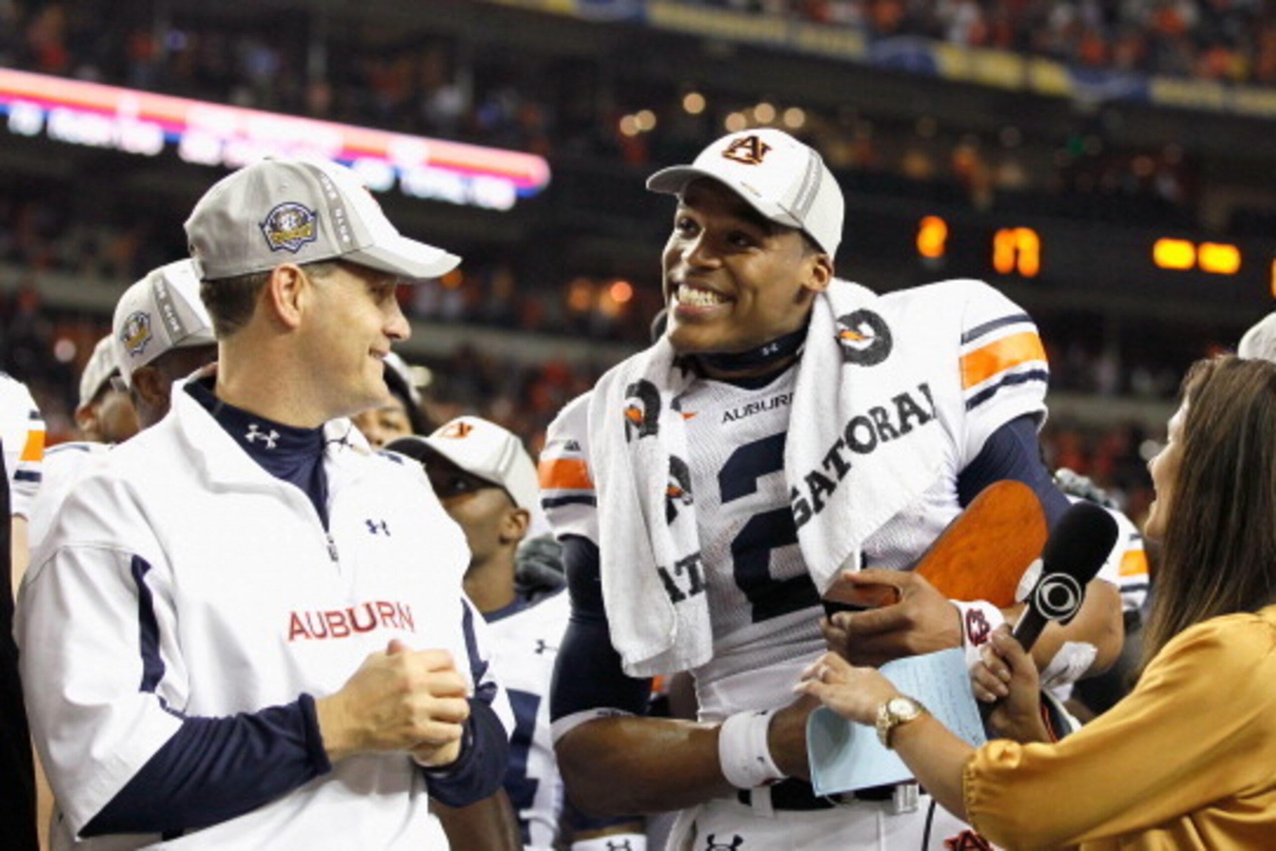 ATLANTA, GA - DECEMBER 04:  CBS sideline reporter Tracy Wolfson (R) and head coach Gene Chizik look on as quarterback Cam Newton #2 of the Auburn Tigers accepts the MVP trophy after their 56-17 win over the South Carolina Gamecocks during the 2010 SEC Cha