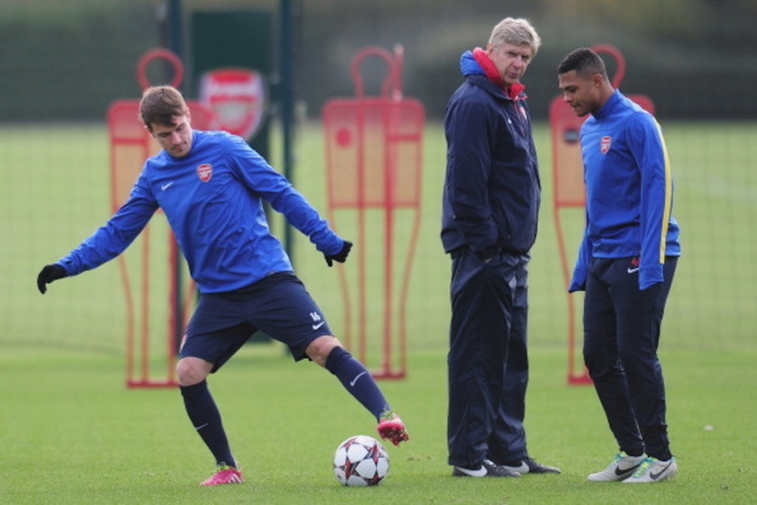 ST ALBANS, ENGLAND - NOVEMBER 25:  Arsenal manager Arsene Wenger talks with player Serge Gnabry as Aaron Ramsey warms up during a training session at London Colney on November 25, 2013 in St Albans, England.  (Photo by Shaun Botterill/Getty Images)