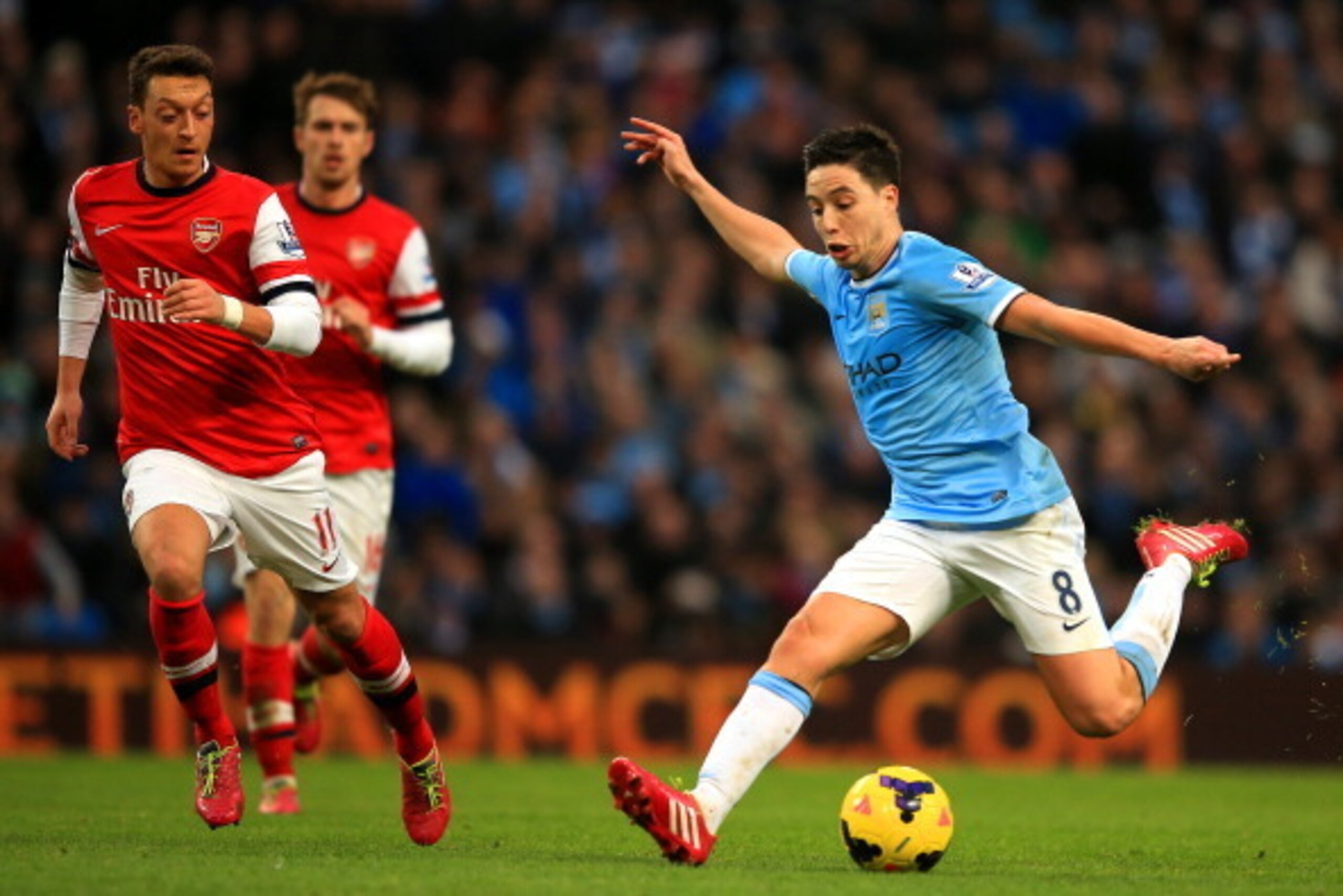 MANCHESTER, ENGLAND - DECEMBER 14: Mesut Oezil of Arsenal marshalls Samir Nasri of Manchester City during the Barclays Premier League match between Manchester City and Arsenal at Etihad Stadium on December 14, 2013 in Manchester, England. (Photo by Richar