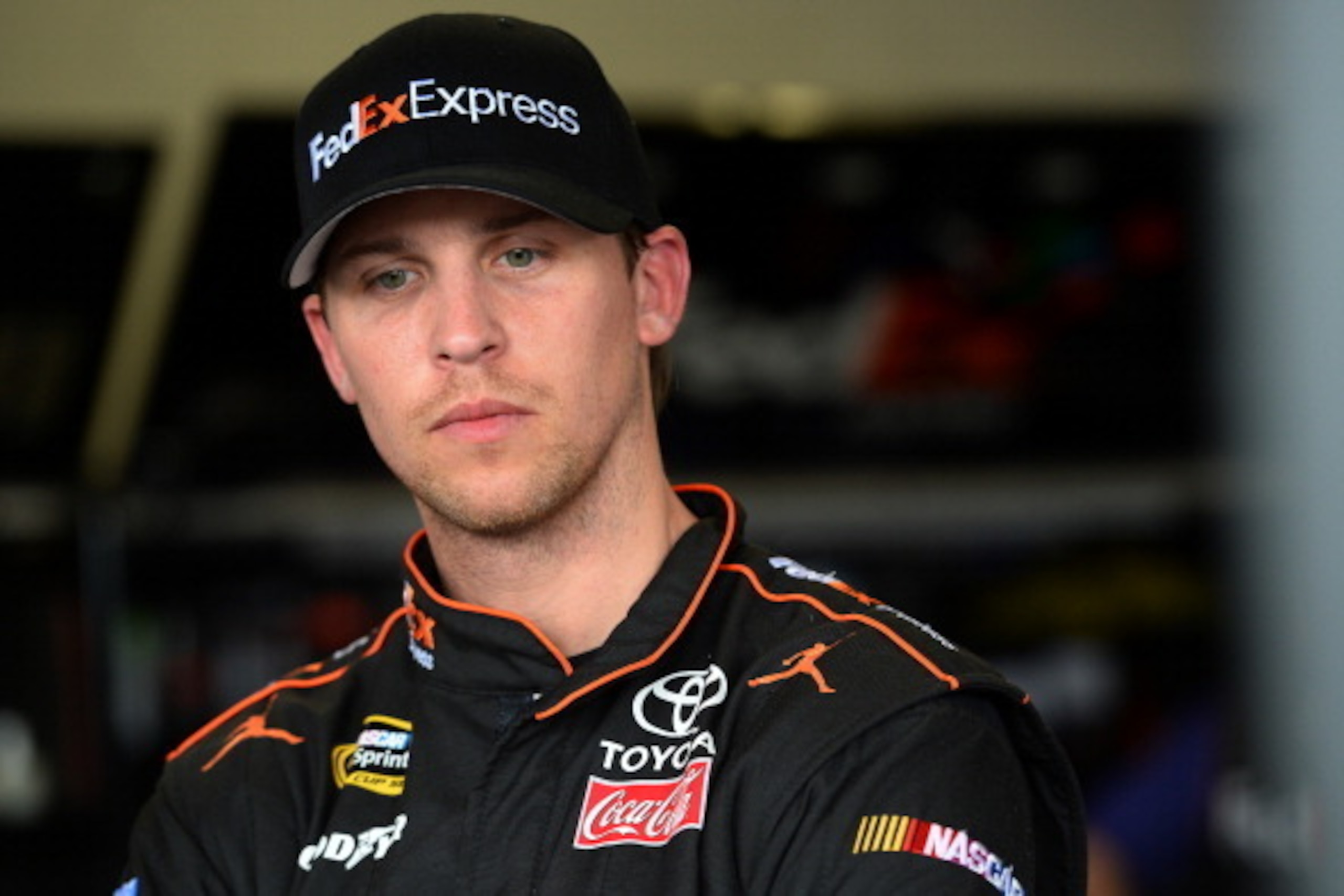 DAYTONA BEACH, FL - FEBRUARY 21:  Denny Hamlin, driver of the #11 FedEx Express Toyota, stands in the garage area during practice for the NASCAR Sprint Cup Series Daytona 500 at Daytona International Speedway on February 21, 2014 in Daytona Beach, Florida