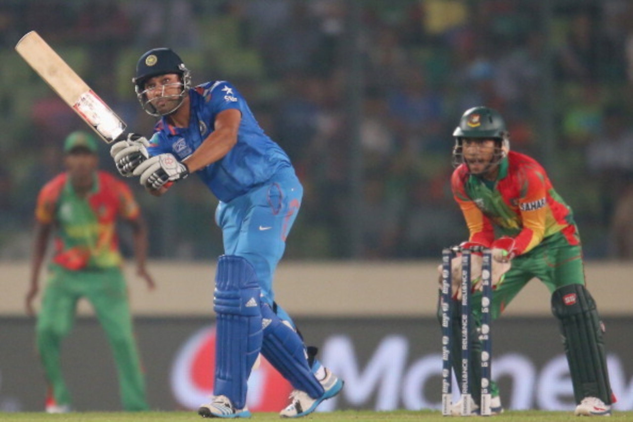 DHAKA, BANGLADESH - MARCH 28: Rohit Sharma of India bats as Mushfiqur Rahim of Bangladesh looks on during the ICC World Twenty20 Bangladesh 2014 match between Bangladesh and India at Sher-e-Bangla Mirpur Stadium on March 28, 2014 in Dhaka, Bangladesh. ( DHAKA, BANGLADESH - MARCH 28: Rohit Sharma of India bats as Mushfiqur Rahim of Bangladesh looks on during the ICC World Twenty20 Bangladesh 2014 match between Bangladesh and India at Sher-e-Bangla Mirpur Stadium on March 28, 2014 in Dhaka, Bangladesh. (