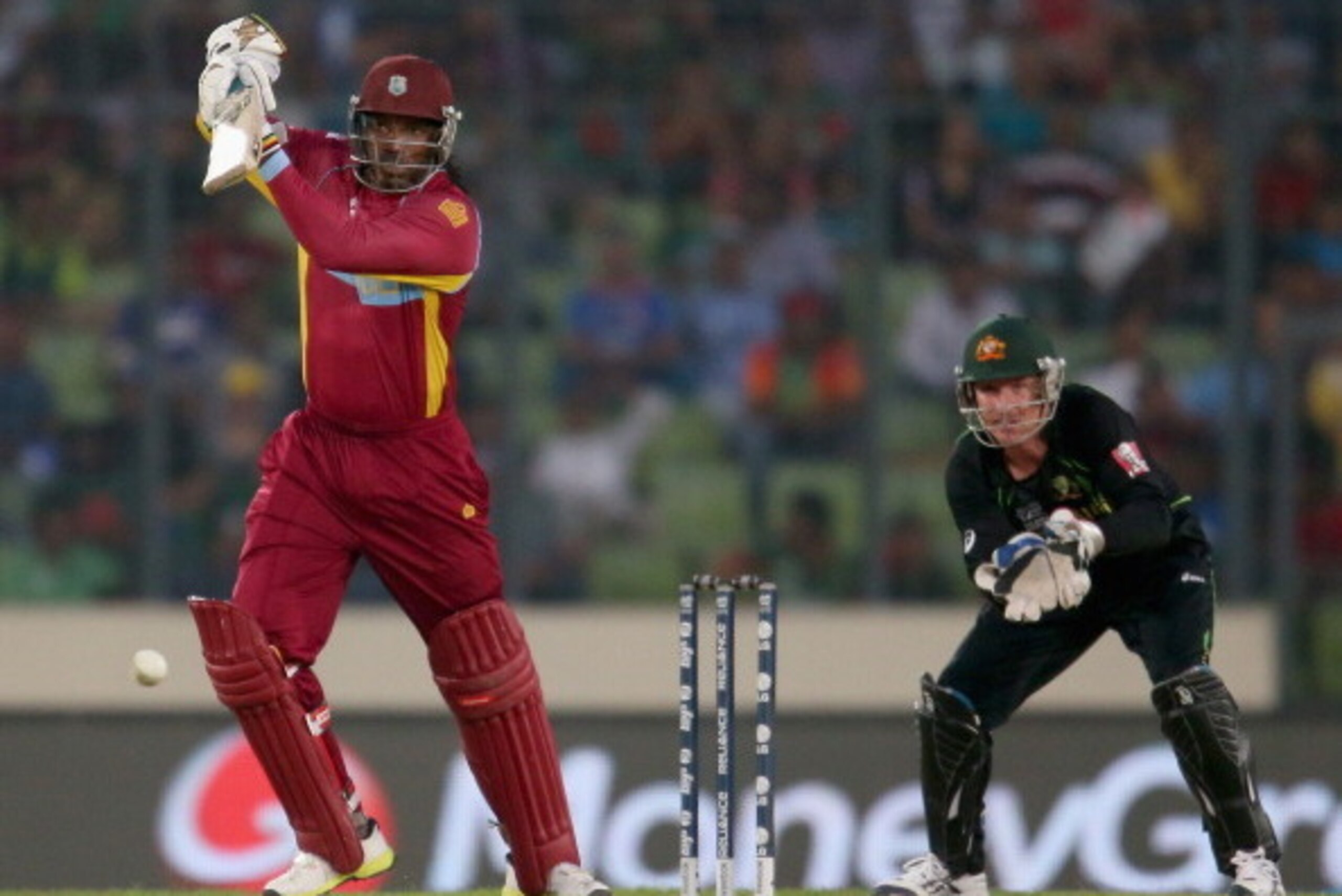 DHAKA, BANGLADESH - MARCH 28: Chris Gayle of the West Indies bats as Brad Haddin of Australia looks on during the ICC World Twenty20 Bangladesh 2014 match between Australia and the West Indies at Sher-e-Bangla Mirpur Stadium on March 28, 2014 in Dhaka, B DHAKA, BANGLADESH - MARCH 28: Chris Gayle of the West Indies bats as Brad Haddin of Australia looks on during the ICC World Twenty20 Bangladesh 2014 match between Australia and the West Indies at Sher-e-Bangla Mirpur Stadium on March 28, 2014 in Dhaka, B