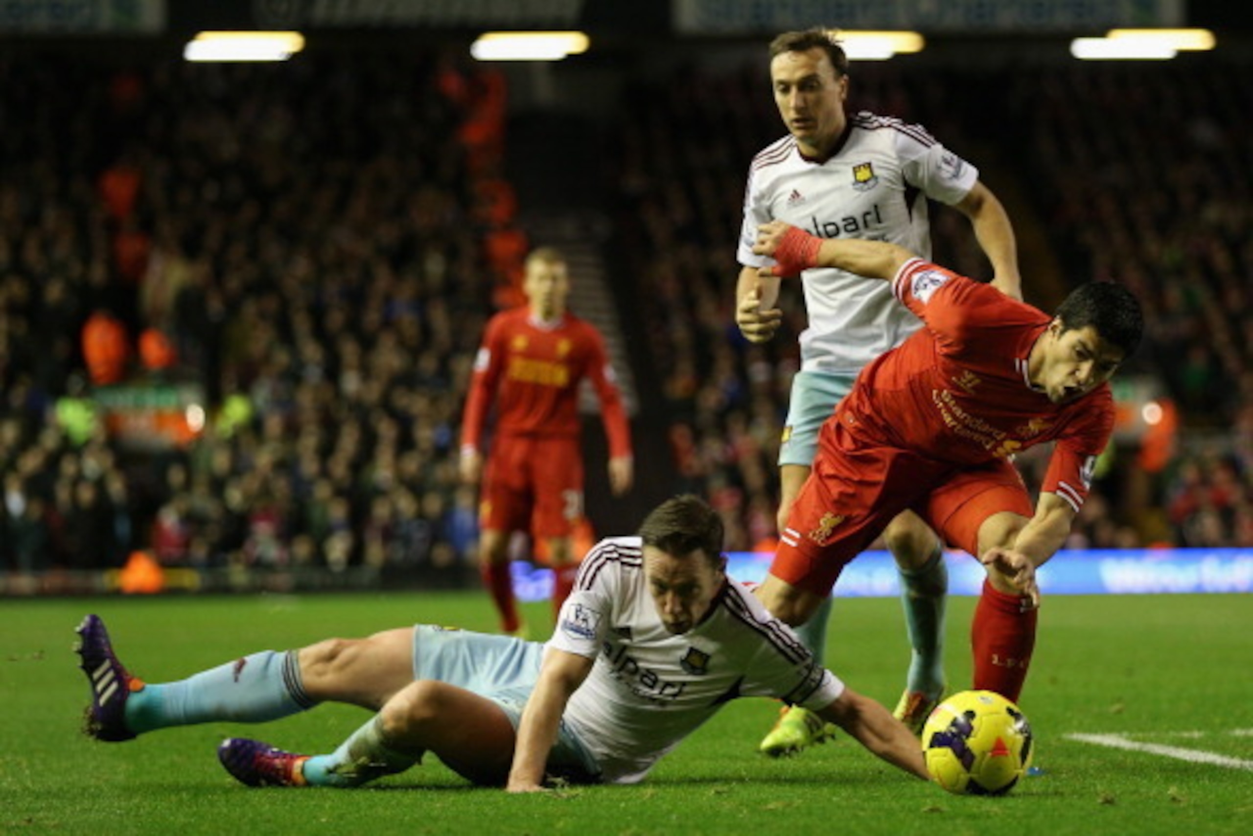 LIVERPOOL, ENGLAND - DECEMBER 07:  Luis Suarez of Liverpool competes with Kevin Nolan of West Ham United during the Barclays Premier League match between Liverpool and West Ham United at Anfield on December 7, 2013 in Liverpool, England.  (Photo by Clive 
