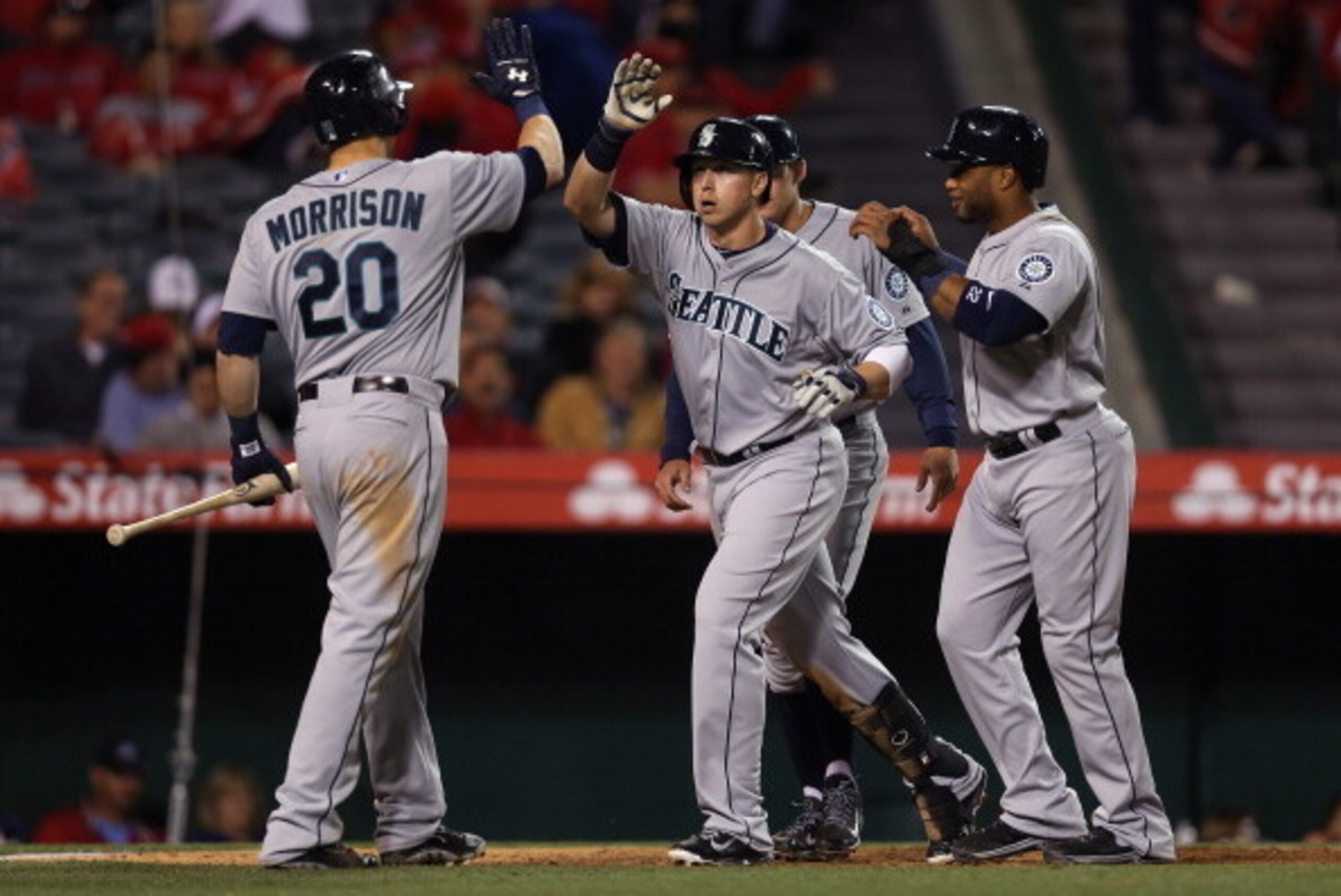 ANAHEIM, CA - MARCH 31:  (L-R) Logan Morrison #20, Justin Smoak #17 and Robinson Cano #22 of the Seattle Mariners celebrate Smoak's three-run home run against the Los Angeles Angels of Anaheim in the ninth inning during Opening Day at Angel Stadium of Ana