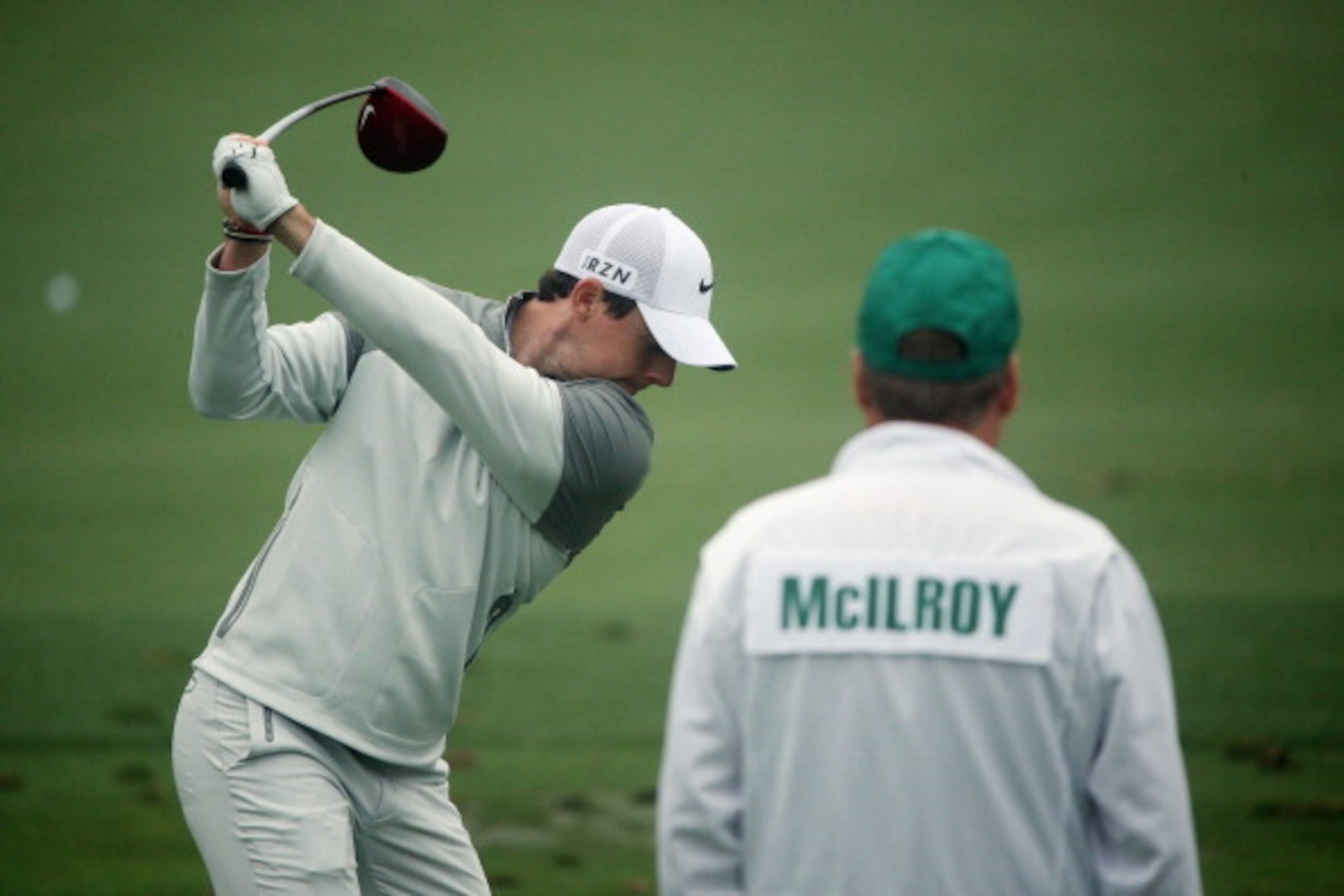 AUGUSTA, GA - APRIL 07:  (L-R) Rory McIlroy of Northern Ireland hits a shot as his caddie, J. P. Fitzgerald, looks on during a practice round prior to the start of the 2014 Masters Tournament at Augusta National Golf Club on April 7, 2014 in Augusta, Geor