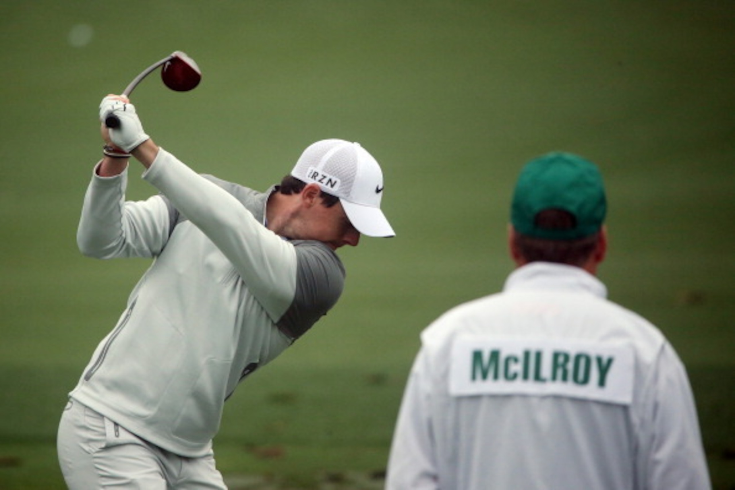 AUGUSTA, GA - APRIL 07: (L-R) Rory McIlroy of Northern Ireland hits a shot as his caddie, J. P. Fitzgerald, looks on during a practice round prior to the start of the 2014 Masters Tournament at Augusta National Golf Club on April 7, 2014 in Augusta, Georg