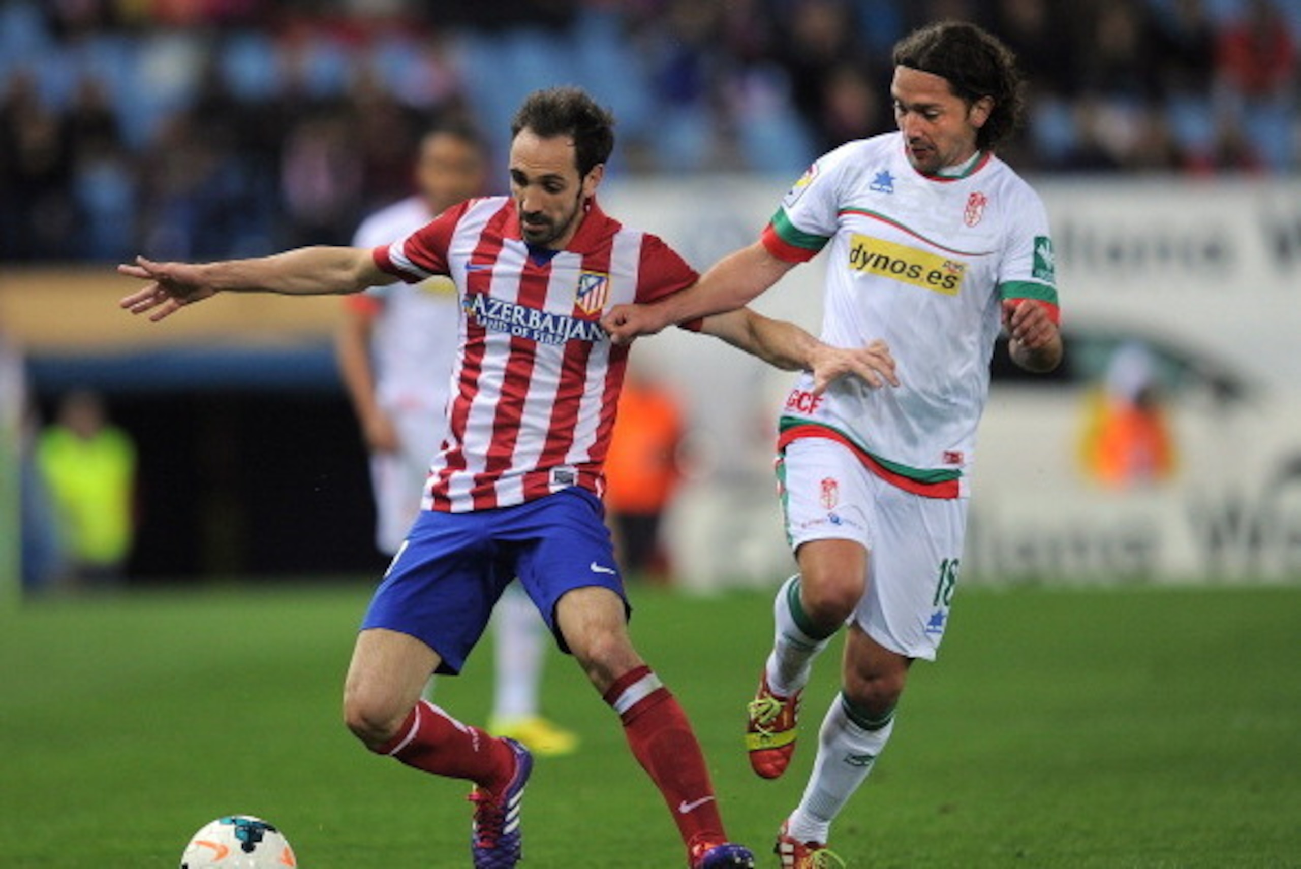 MADRID, SPAIN - MARCH 26:  Juanfran (L) of Club Atletico de Madrid is tackled by Manuel Iturra of Granada CF during the La Liga match between Club Atletico de Madrid and Granada CF at Vicente Calderon Stadium on March 26, 2014 in Madrid, Spain.  (Photo by