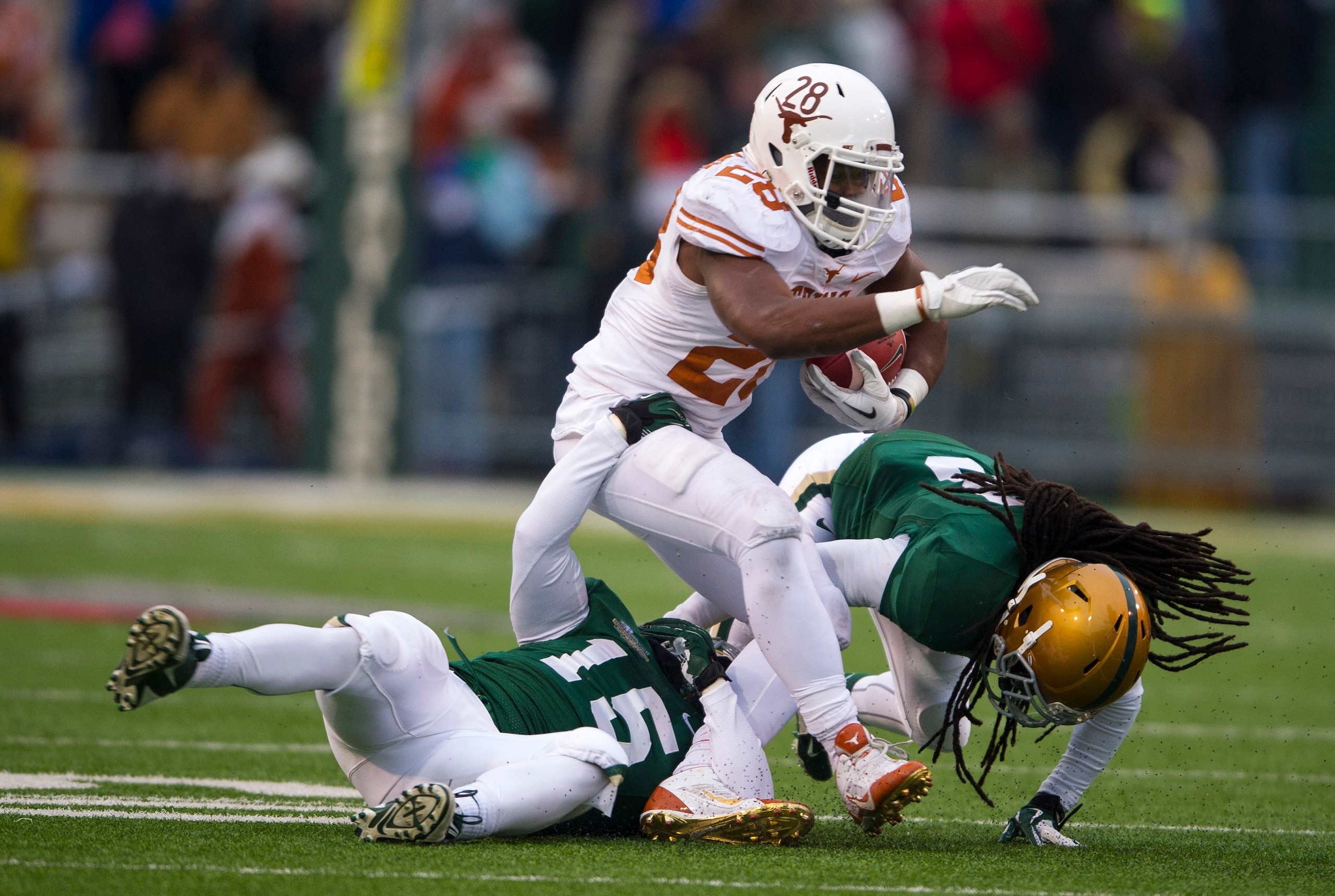 Dec 7, 2013; Waco, TX, USA; Texas Longhorns running back Malcolm Brown (28) tries to elude Baylor Bears linebacker Brody Trahan (15) and cornerback K.J. Morton (8) during the second quarter at Floyd Casey Stadium. Mandatory Credit: Jerome Miron-USA TODAY