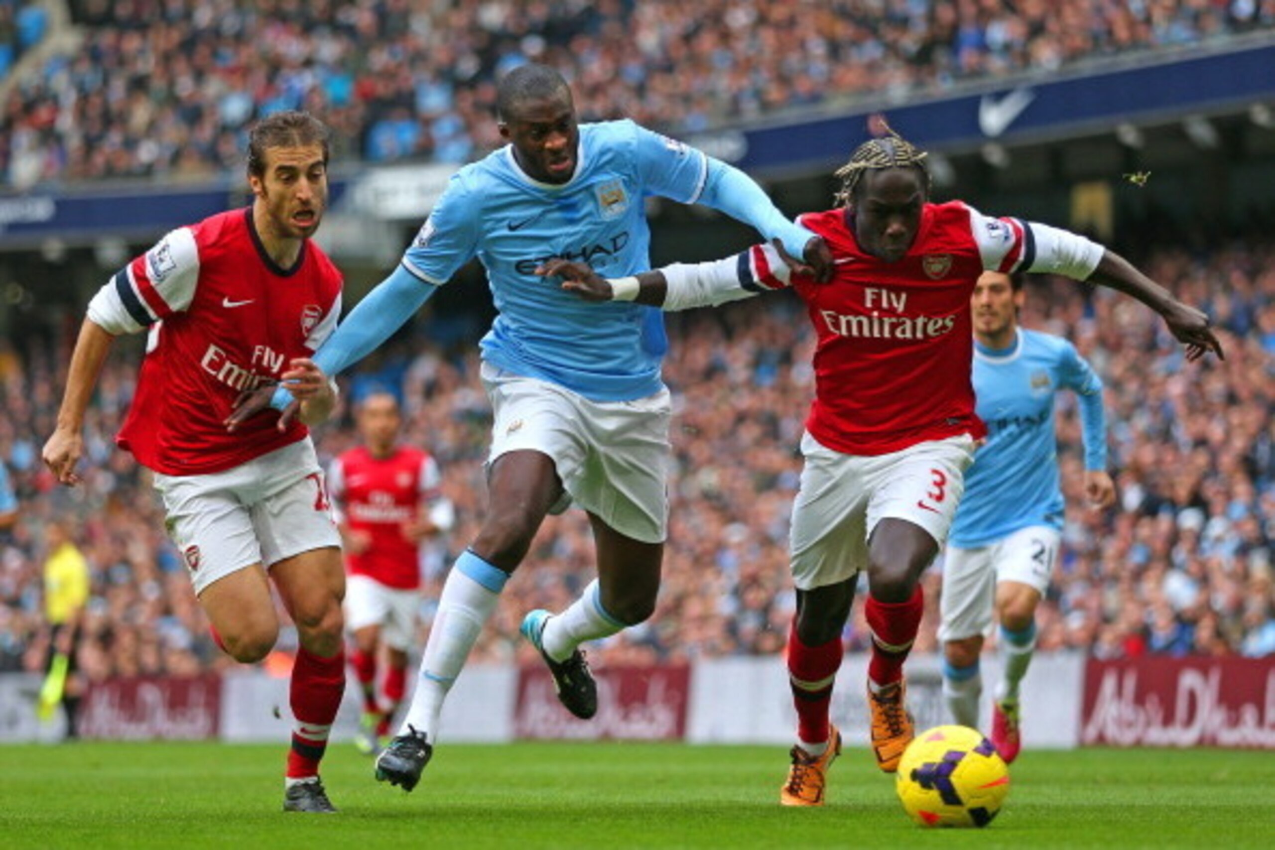 MANCHESTER, ENGLAND - DECEMBER 14:  Yaya Toure of Manchester City is closed down by Mathieu Flamini and Bacary Sagna of Arsenal  during the Barclays Premier League match between Manchester City and Arsenal at Etihad Stadium on December 14, 2013 in Manches