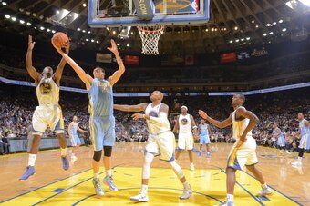 OAKLAND, CA - APRIL 10: Timofey Mozgov #25 of the Denver Nuggets rebounds against Draymond Green #23 of the Golden State Warriors on April 10, 2014 at Oracle Arena in Oakland, California. NOTE TO USER: User expressly acknowledges and agrees that, by downl