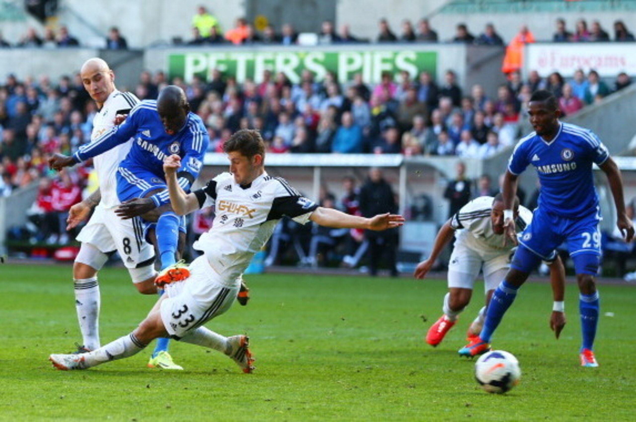 SWANSEA, WALES - APRIL 13:  Demba Ba of Chelsea takes a shot on goal as Ben Davies of Swansea slides in during the Barclays Premier League match between Swansea City and Chelsea at Liberty Stadium on April 13, 2014 in Swansea, Wales.  (Photo by Michael St