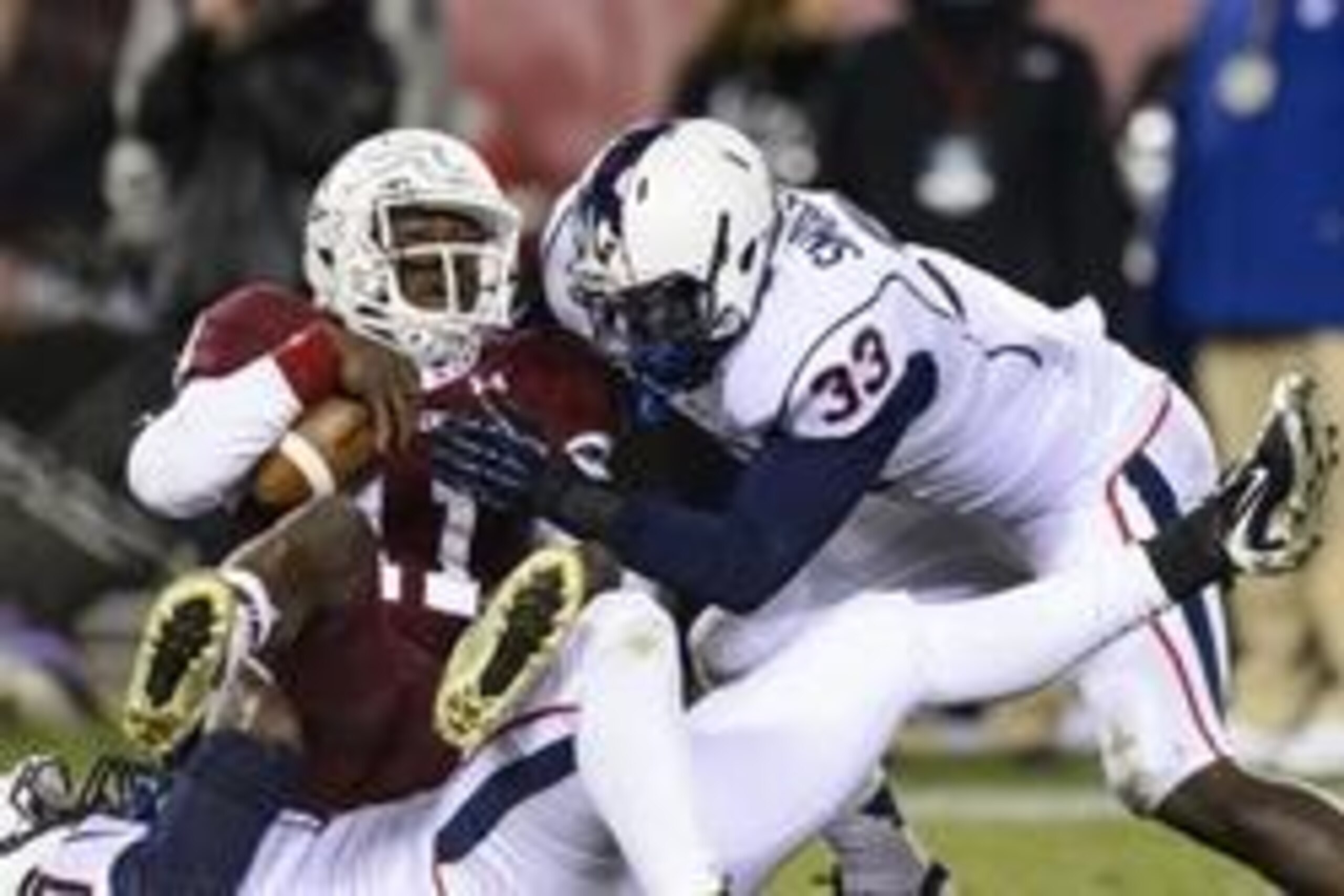 Nov 23, 2013; Philadelphia, PA, USA; Connecticut Huskies linebacker Yawin Smallwood (33) assists defensive end Reuben Frank (47) in a tackle of Temple Owls quarterback P.J. Walker (11) during the third quarter at Lincoln Financial Field. UCONN defeated Te
