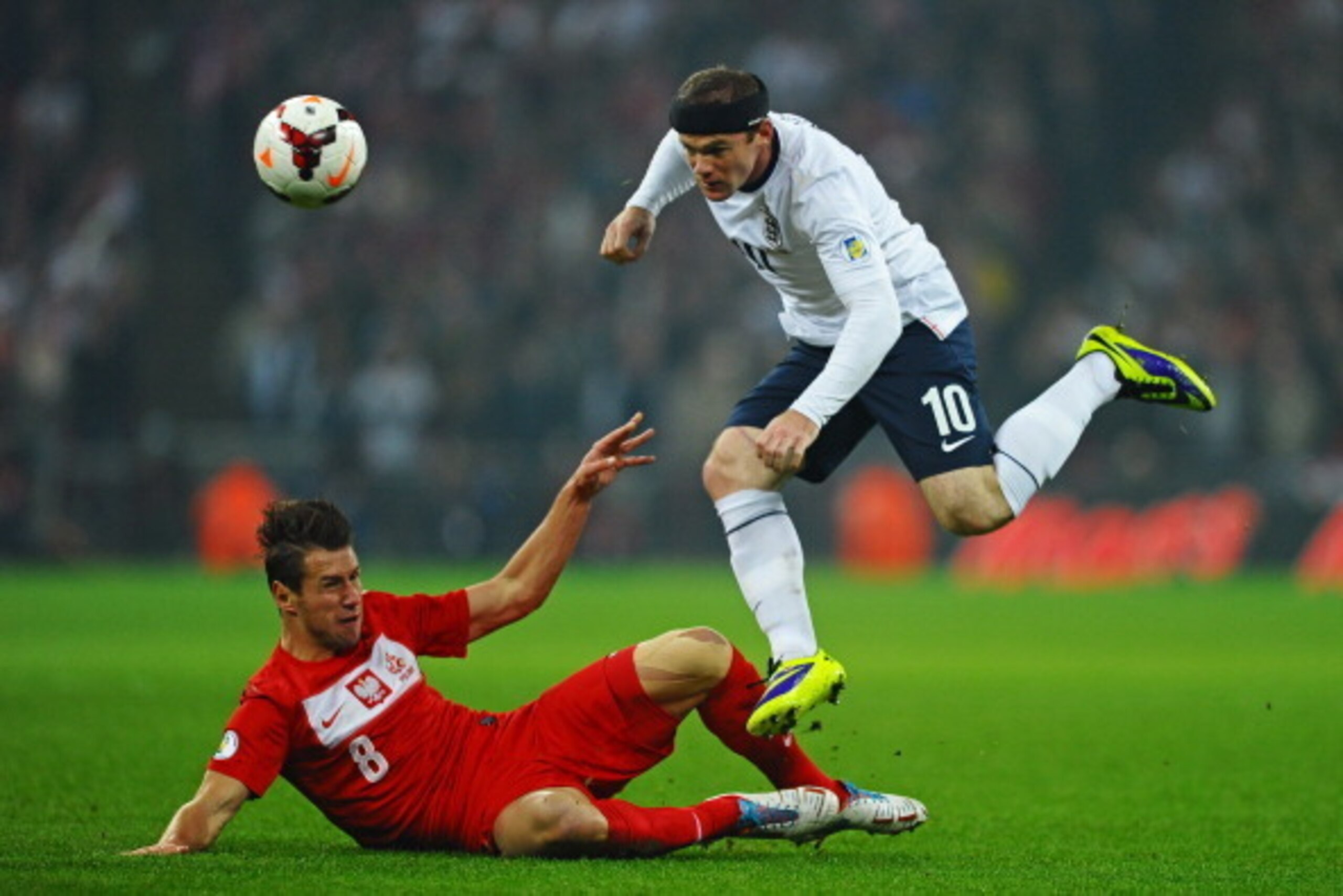 LONDON, ENGLAND - OCTOBER 15:  Wayne Rooney of England hurdles the challenge from Grzegorz Krychowiak of Poland during the FIFA 2014 World Cup Qualifying Group H match between England and Poland at Wembley Stadium on October 15, 2013 in London, England.  
