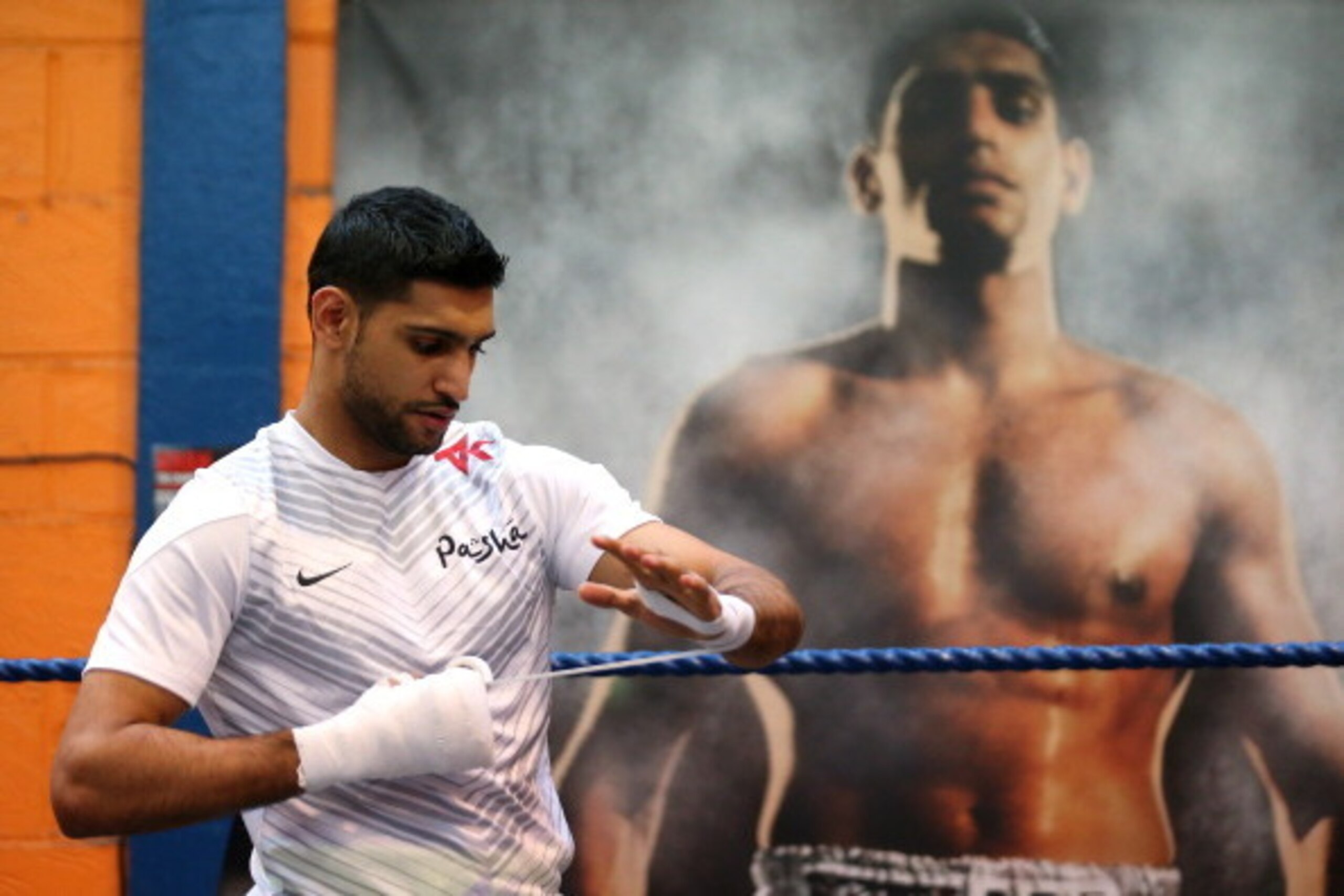 BOLTON, ENGLAND - MARCH 24:  Amir Khan tapes his hands up prior to a media workout at the Gloves Community Centre on March 24, 2014 in Bolton, England.  (Photo by Alex Livesey/Getty Images)