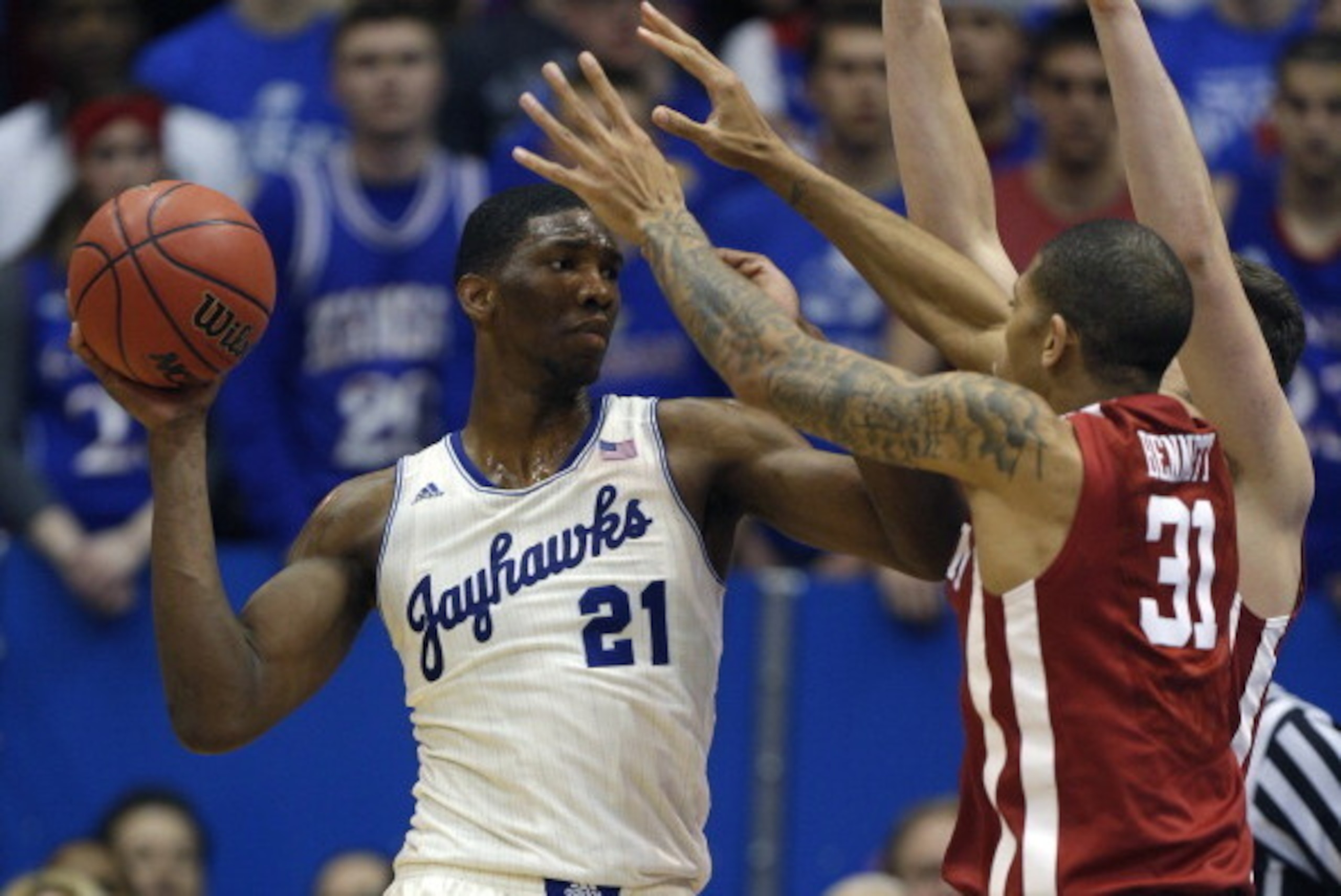 LAWRENCE, KS - FEBRUARY 24:  Joel Embiid #21 of the Kansas Jayhawks looks to pass the ball against D.J. Bennett #31 of the Oklahoma Sooners in the second half at Allen Fieldhouse on February 24, 2014 in Lawrence, Kansas.  Kansas won 83-75. (Photo by Ed Zu