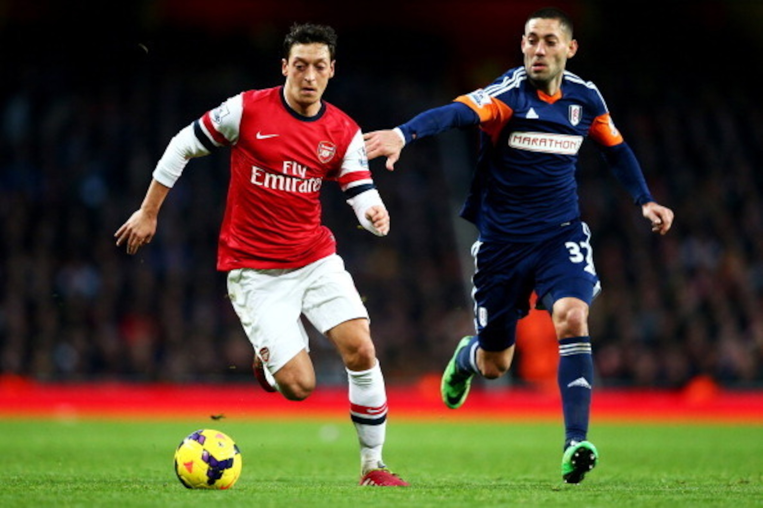 LONDON, ENGLAND - JANUARY 18:  Mesut Oezil of Arsenal is chased by Clint Dempsey of Fulham during the Barclays Premier League match between Arsenal and Fulham at Emirates Stadium on January 18, 2014 in London, England.  (Photo by Clive Mason/Getty Images)