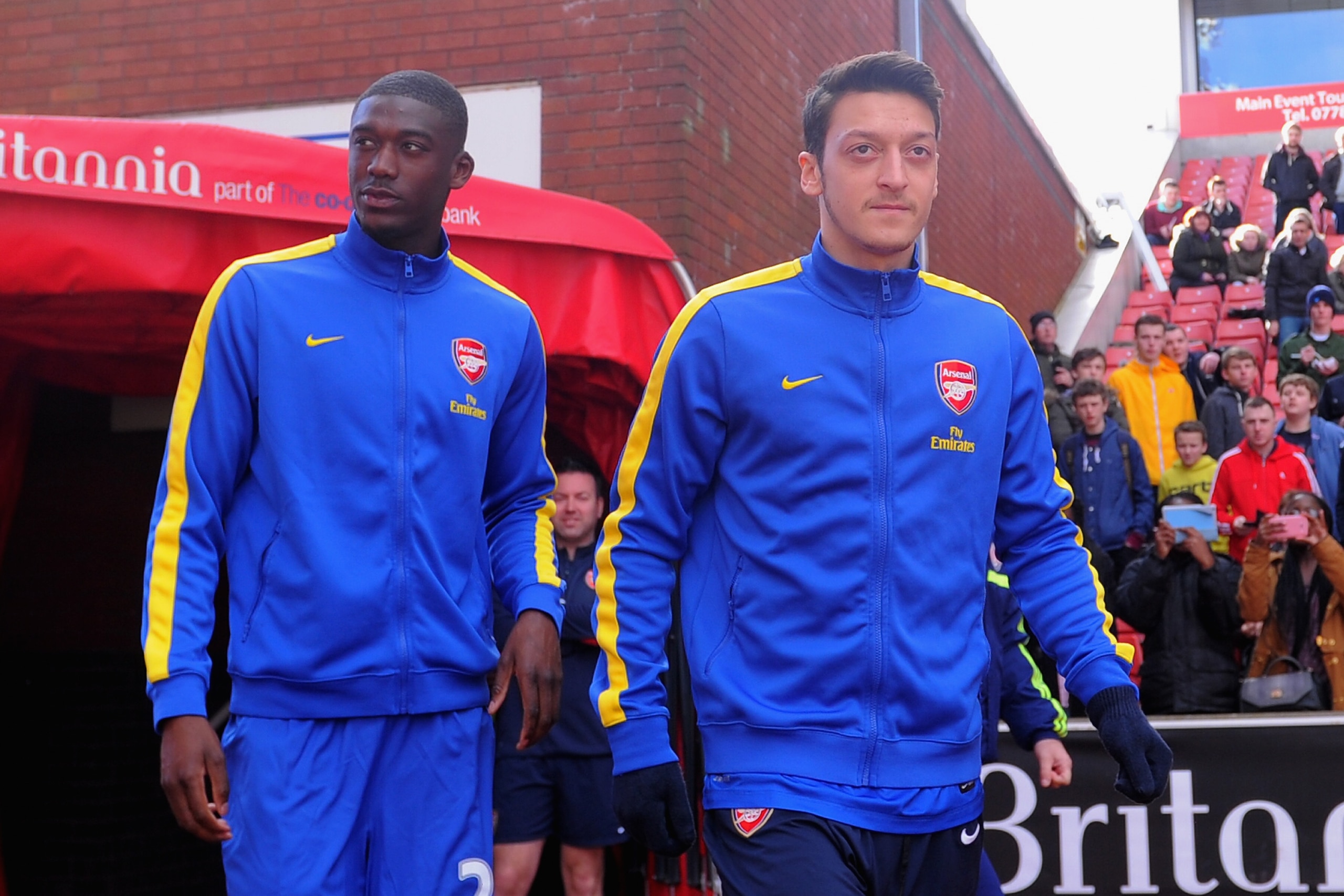 STOKE ON TRENT, ENGLAND - MARCH 01:  Mesut Ozil of Arsenal (R) walks out to warm up with team-mate Yaya Sanogo prior to the Barclays Pemier League match between Stoke City and Arsenal at the Britannia Stadium on March 1, 2014 in Stoke on Trent, England.