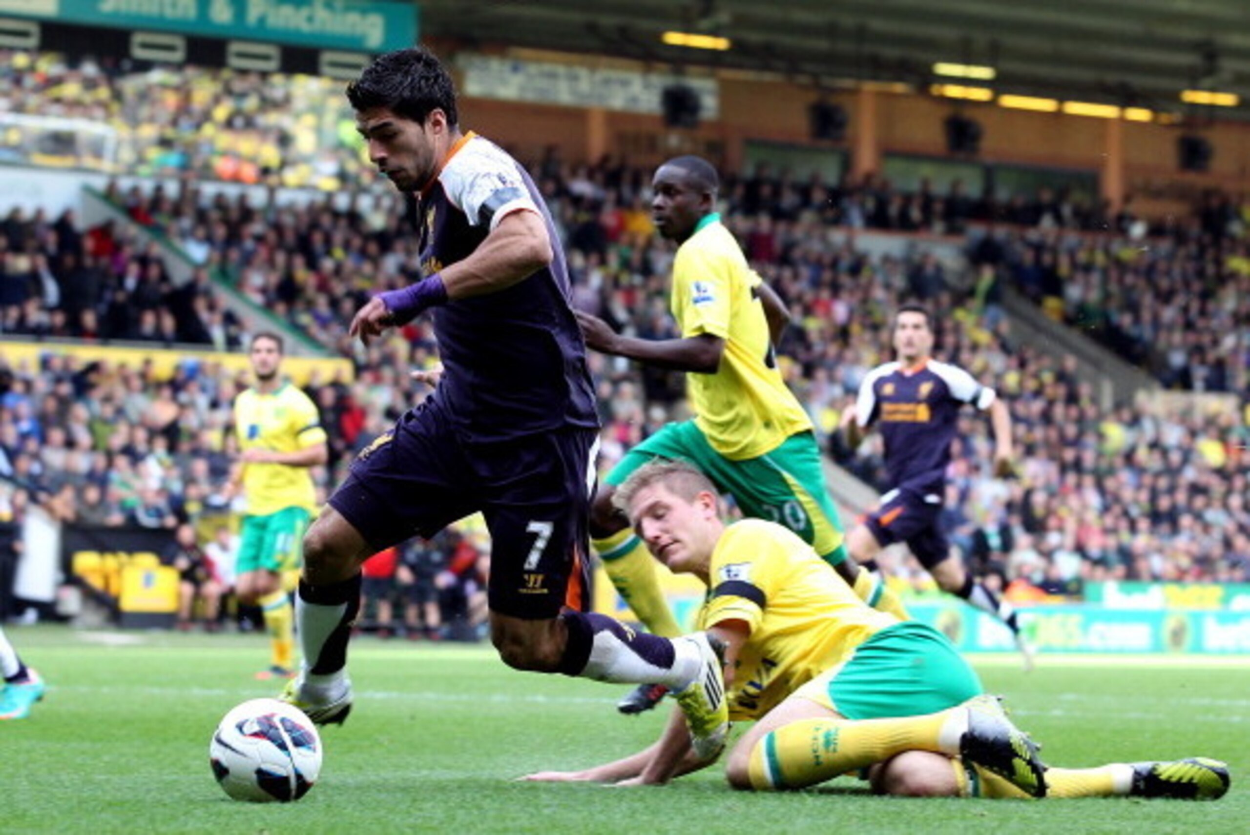 NORWICH, ENGLAND - SEPTEMBER 29:   Luis Suarez of Liverpool rounds Michael Turner of Norwich City to setup a goal for team-mate Nuri Sahin during the Barclays Premier League match between Norwich City and Liverpool at Carrow Road on September 29, 2012 in 