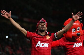 MANCHESTER, ENGLAND - APRIL 22:  Patrice Evra of Manchester United celebrates victory and winning the Premier League title with mascot Fred the Red after the Barclays Premier League match between Manchester United and Aston Villa at Old Trafford on April 