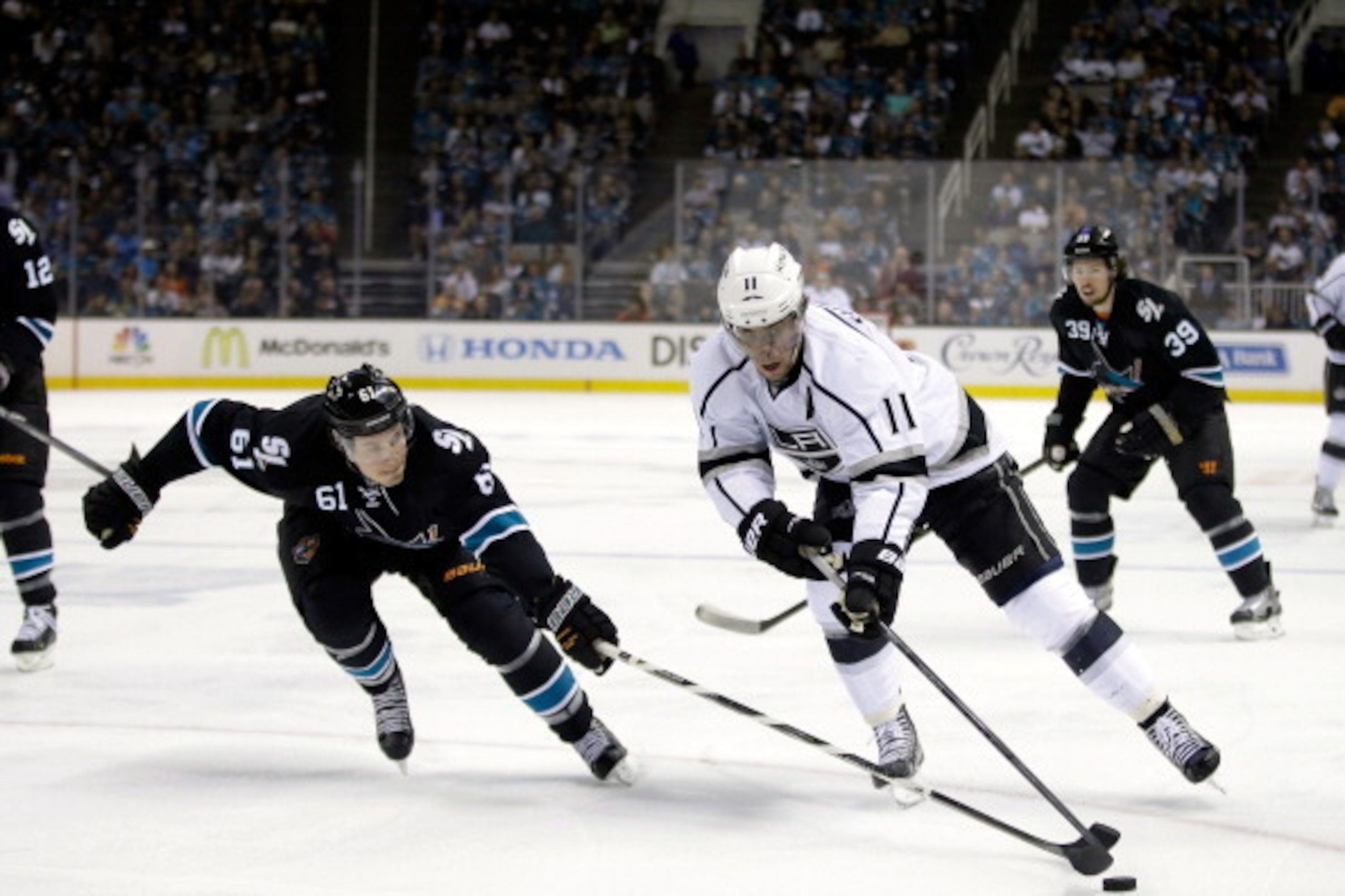 SAN JOSE, CA - APRIL 20:  Justin Braun #61 of the San Jose Sharks and Anze Kopitar #11 of the Los Angeles Kings go for the puck in Game Two of the First Round of the 2014 NHL Stanley Cup Playoffs at SAP Center on April 20, 2014 in San Jose, California.  (