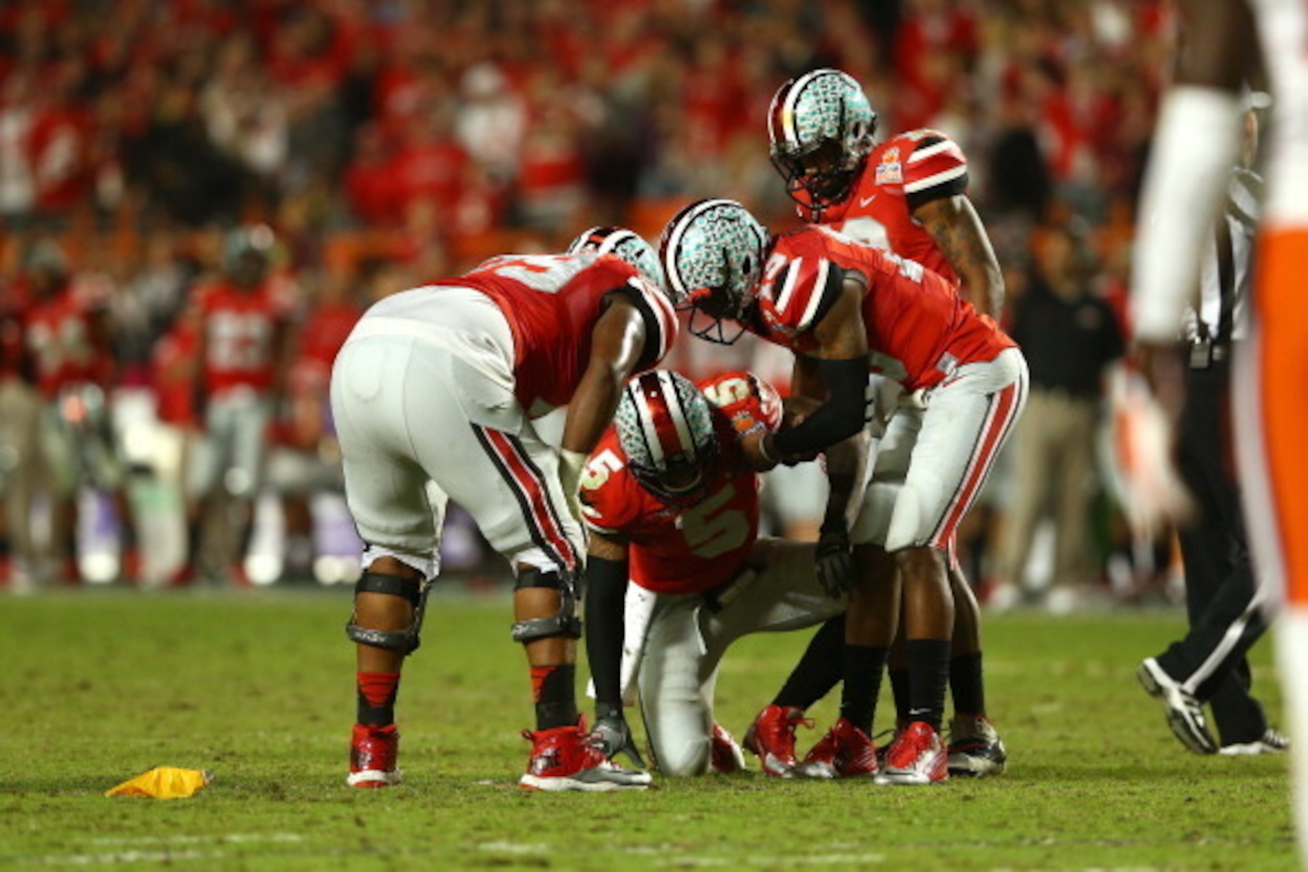 MIAMI GARDENS, FL - JANUARY 03: Braxton Miller #5 of the Ohio State Buckeyes is helped up by teammates after a play in the fourth quarter against the Clemson Tigers during the Discover Orange Bowl at Sun Life Stadium on January 3, 2014 in Miami Gardens, F