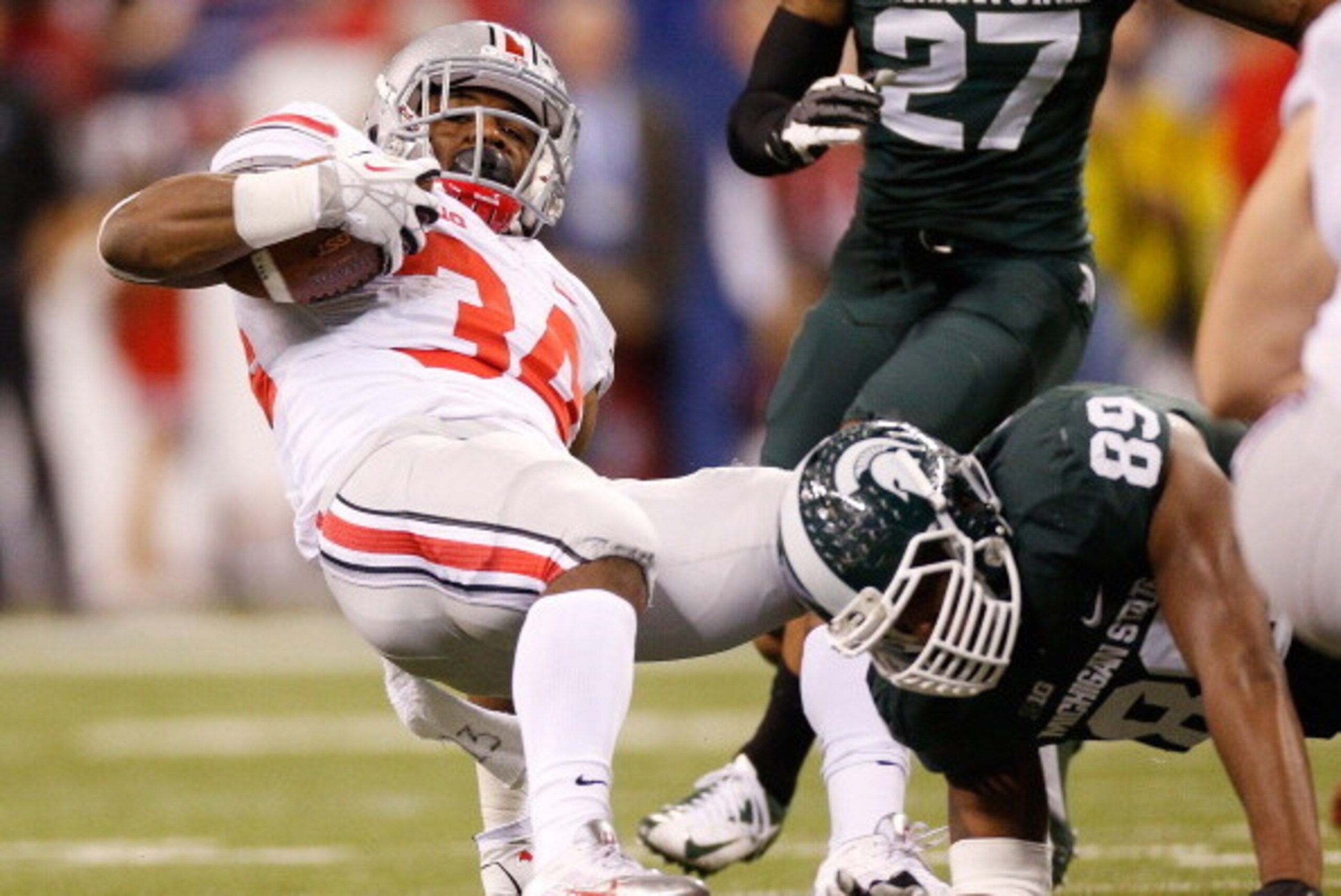 INDIANAPOLIS, IN - DECEMBER 07:  Shilique Calhoun #89 of the Michigan State Spartans trips up Carlos Hyde #34 of the Ohio State Buckeyes during the Big 10 Conference Championship Game at Lucas Oil Stadium on December 7, 2013 in Indianapolis, Indiana.  (Ph