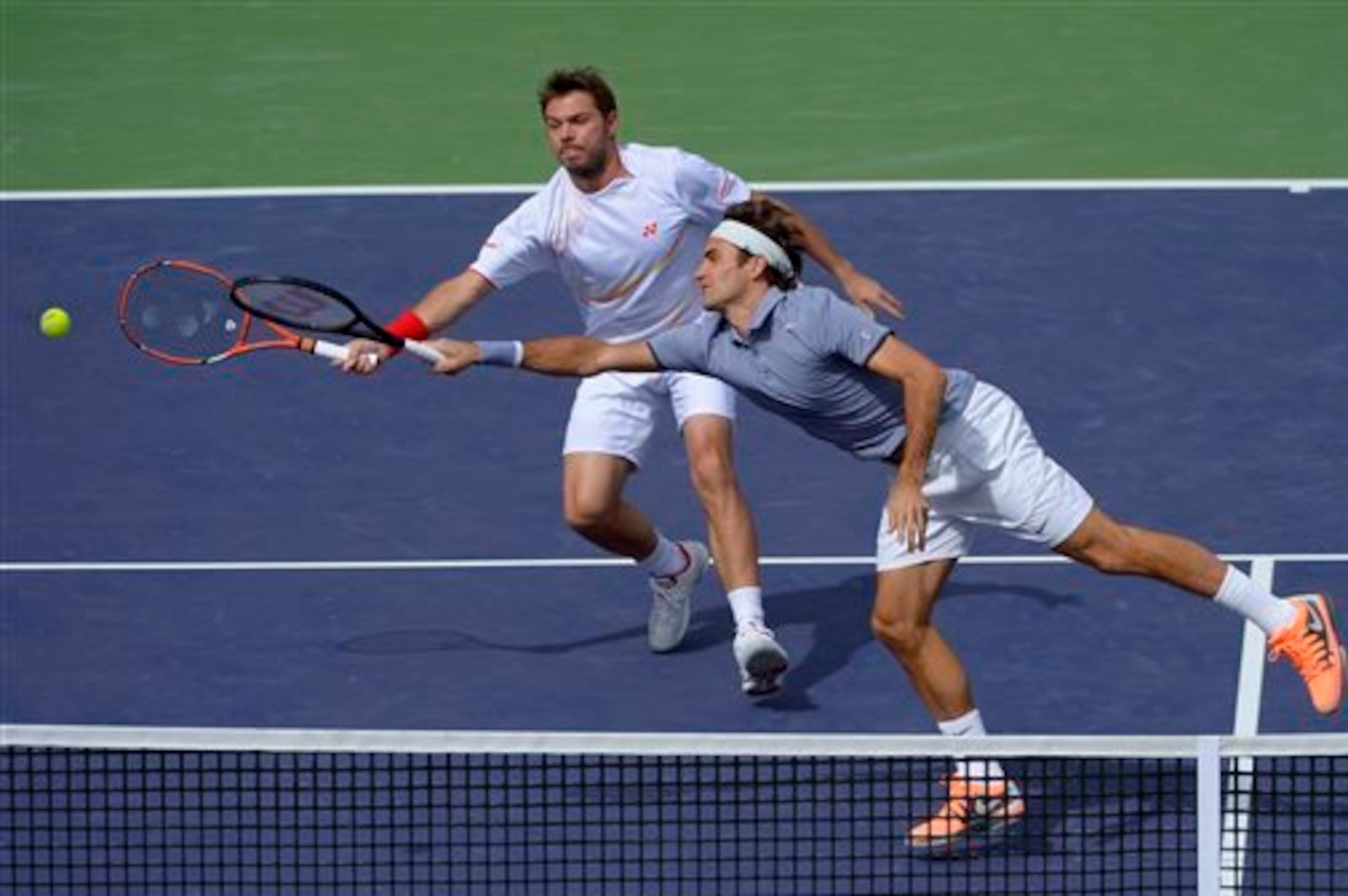 Stanislas Wawrinka and Roger Federer both reach for ball during a doubles match at Indian Wells.