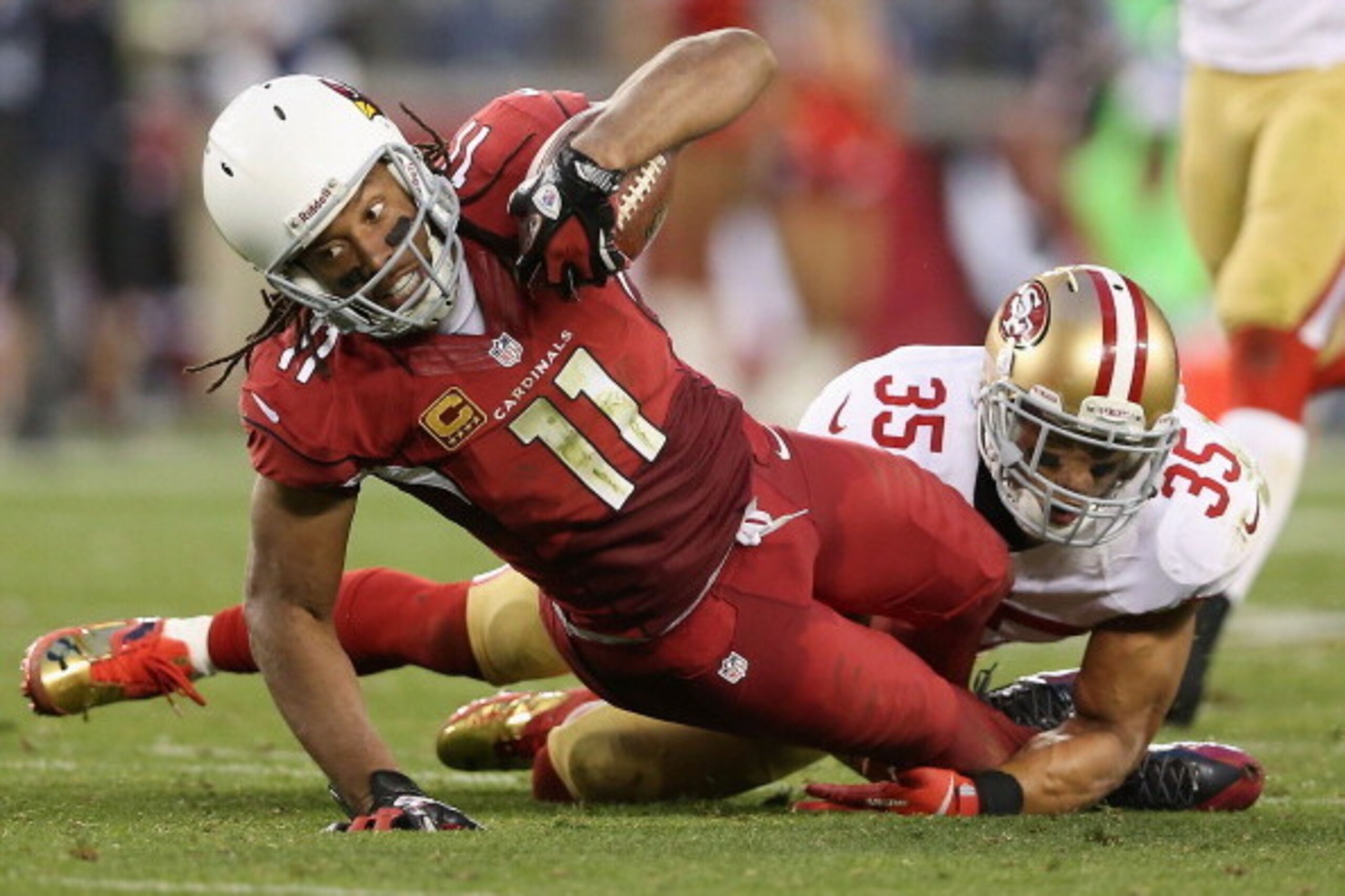 GLENDALE, AZ - DECEMBER 29:  Wide receiver Larry Fitzgerald #11 of the Arizona Cardinals is tackled by free safety Eric Reid #35 of the San Francisco 49ers after a reception during the NFL game at the University of Phoenix Stadium on December 29, 2013 in 