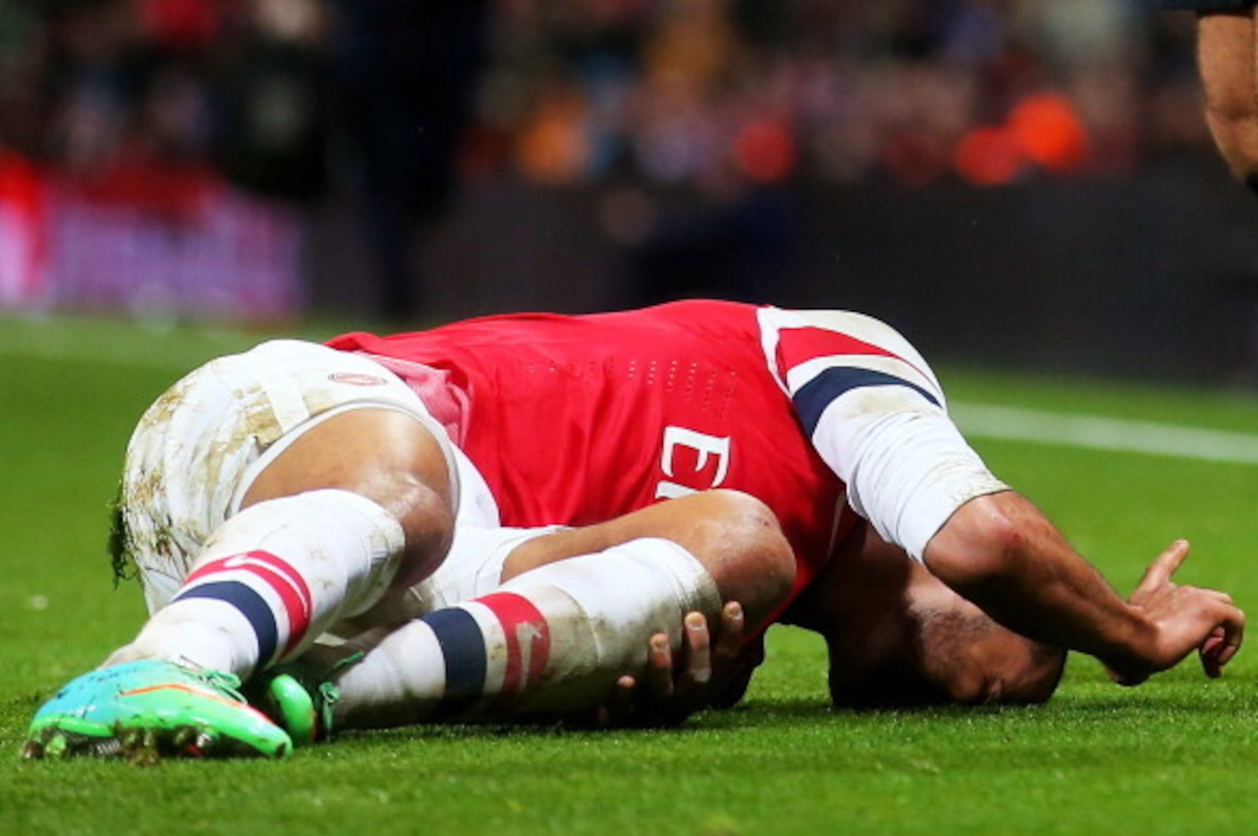 LONDON, ENGLAND - JANUARY 04:   (EDITORS NOTE: Retransmission of image #460558025 with an alternate crop) Theo Walcott of Arsenal lies injured on the pitch during the Budweiser FA Cup third round match between Arsenal and Tottenham Hotspur at Emirates Sta