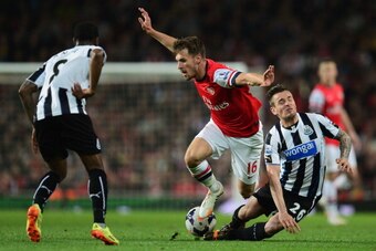 LONDON, ENGLAND - APRIL 28:  Aaron Ramsey of Arsenal takes on Vurnon Anita (L) and Mathieu Debuchy of Newcastle United (R) during the Barclays Premier League match between Arsenal and Newcastle United at Emirates Stadium on April 28, 2014 in London, Engla