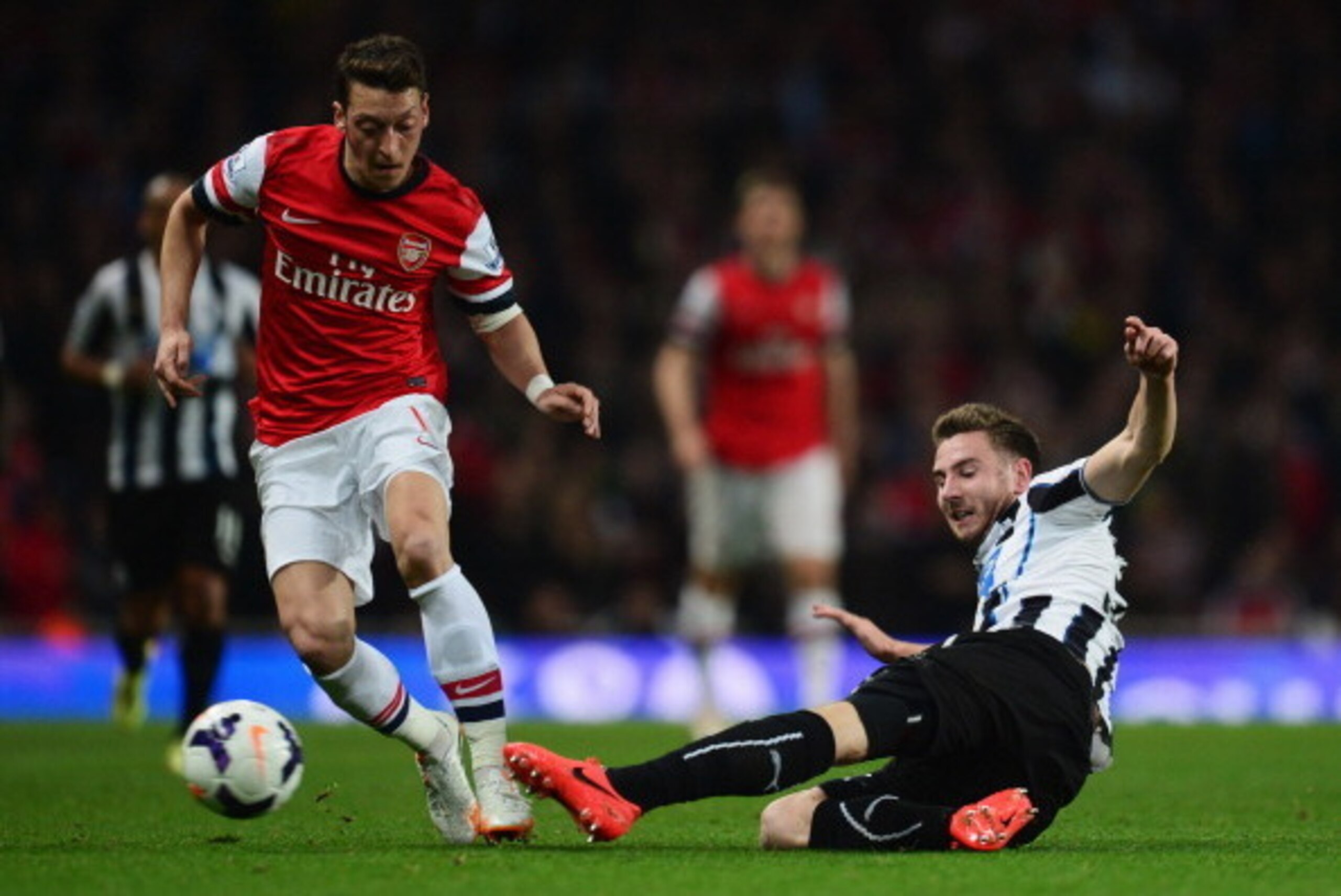 LONDON, ENGLAND - APRIL 28:  Paul Dummett of Newcastle United tackles Mesut Oezil of Arsenal during the Barclays Premier League match between Arsenal and Newcastle United at Emirates Stadium on April 28, 2014 in London, England.  (Photo by Jamie McDonald/