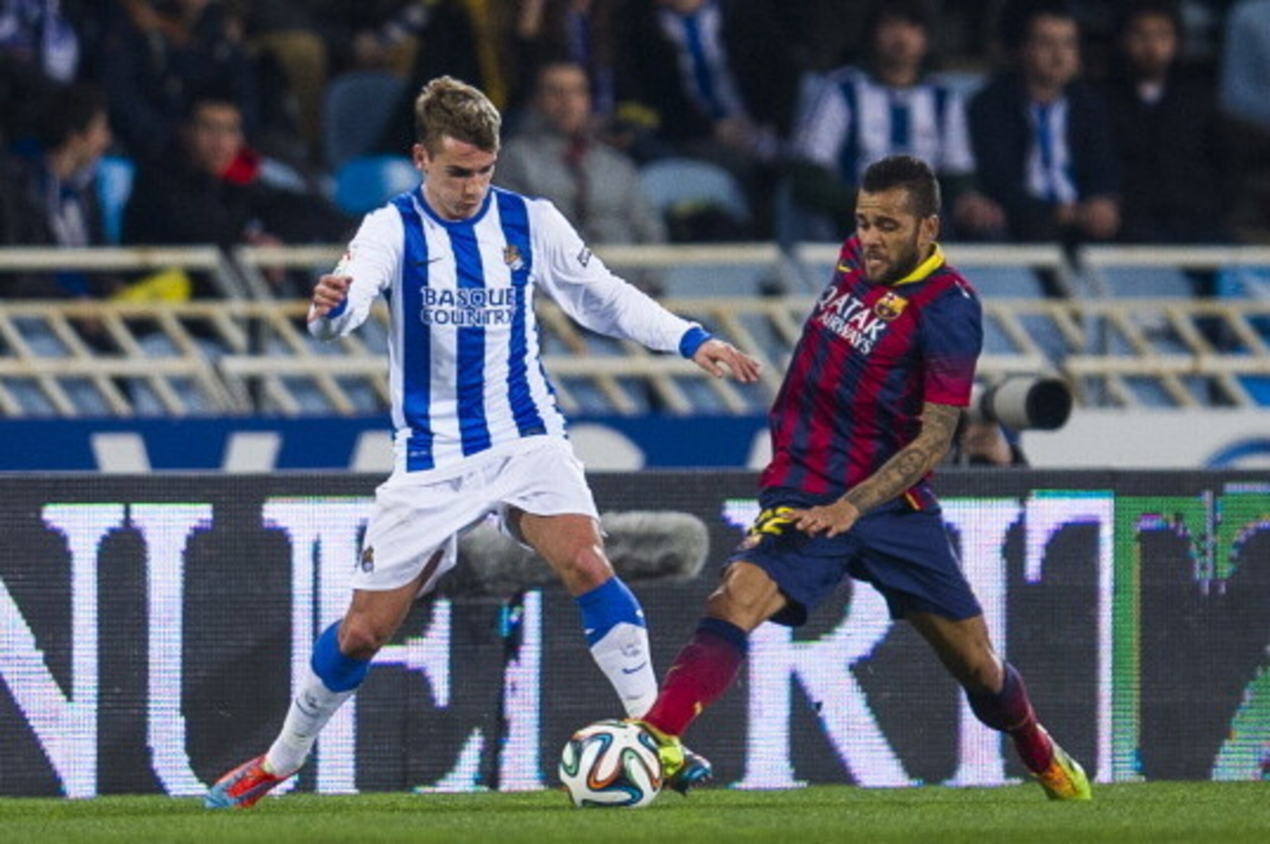 SAN SEBASTIAN, SPAIN - FEBRUARY 12:  Dani Alves of FC Barcelona duels for the ball with Antoine Griezmann of Real Sociedad during the Copa del Rey Semi-Final first leg match between Real Sociedad and Barcelona at Estadio Anoeta  on February 12, 2014 in Sa
