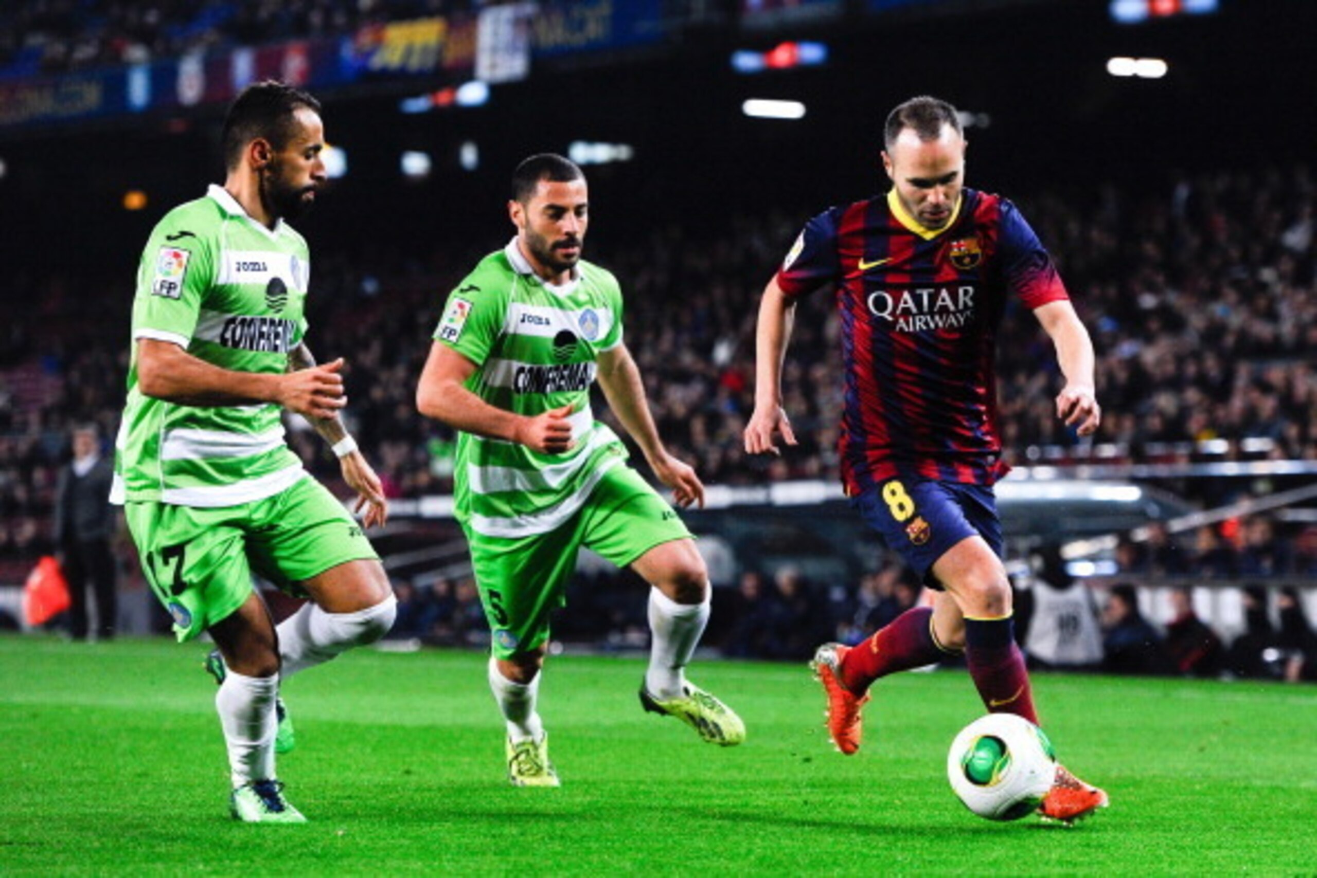 BARCELONA, SPAIN - JANUARY 08: Andres Iniesta of FC Barcelona duels for the ball with Diego Castro (L) and Mehdi Lacen of Getafe CF during the Copa del Rey round of 16 first leg match between FC Barcelona and Getafe CF at Camp Nou on January 8, 2014 in Ba