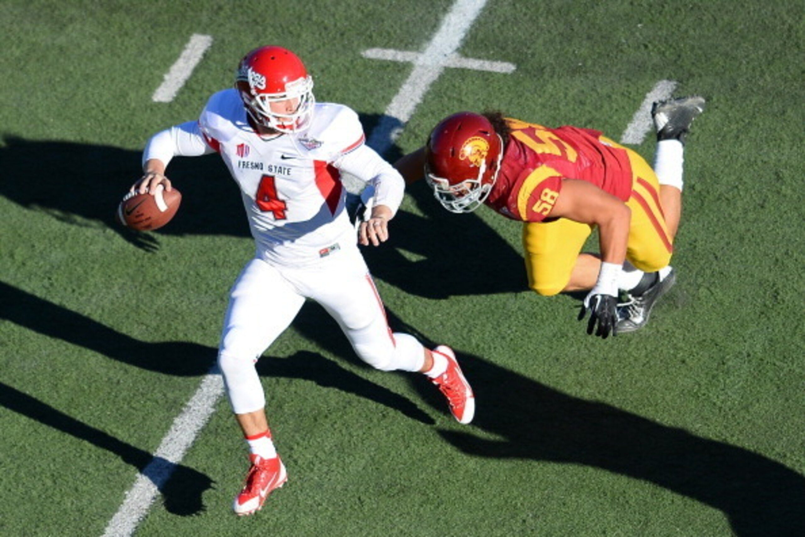LAS VEGAS, NV - DECEMBER 21:  Quarterback Derek Carr #4 of the Fresno State Bulldogs scrambles under pressure from J.R. Tavai #58 of the USC Trojans during the Royal Purple Las Vegas Bowl at Sam Boyd Stadium on December 21, 2013 in Las Vegas, Nevada. USC 