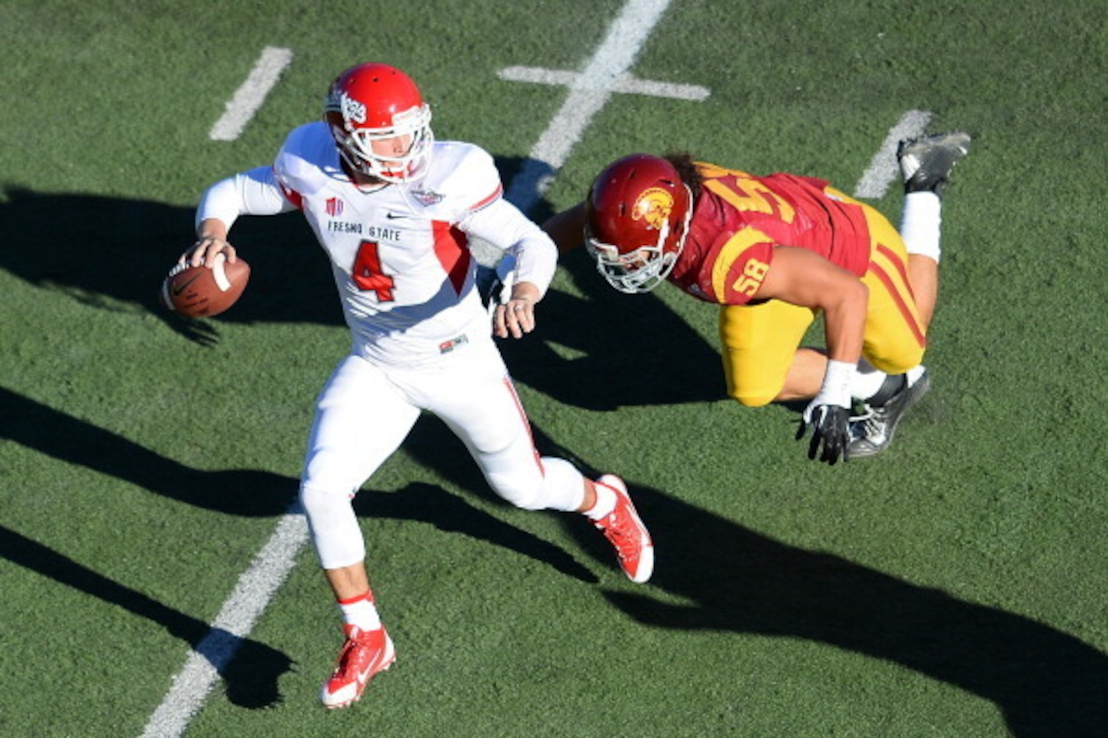 LAS VEGAS, NV - DECEMBER 21: Quarterback Derek Carr #4 of the Fresno State Bulldogs scrambles under pressure from J.R. Tavai #58 of the USC Trojans during the Royal Purple Las Vegas Bowl at Sam Boyd Stadium on December 21, 2013 in Las Vegas, Nevada. USC LAS VEGAS, NV - DECEMBER 21: Quarterback Derek Carr #4 of the Fresno State Bulldogs scrambles under pressure from J.R. Tavai #58 of the USC Trojans during the Royal Purple Las Vegas Bowl at Sam Boyd Stadium on December 21, 2013 in Las Vegas, Nevada. USC