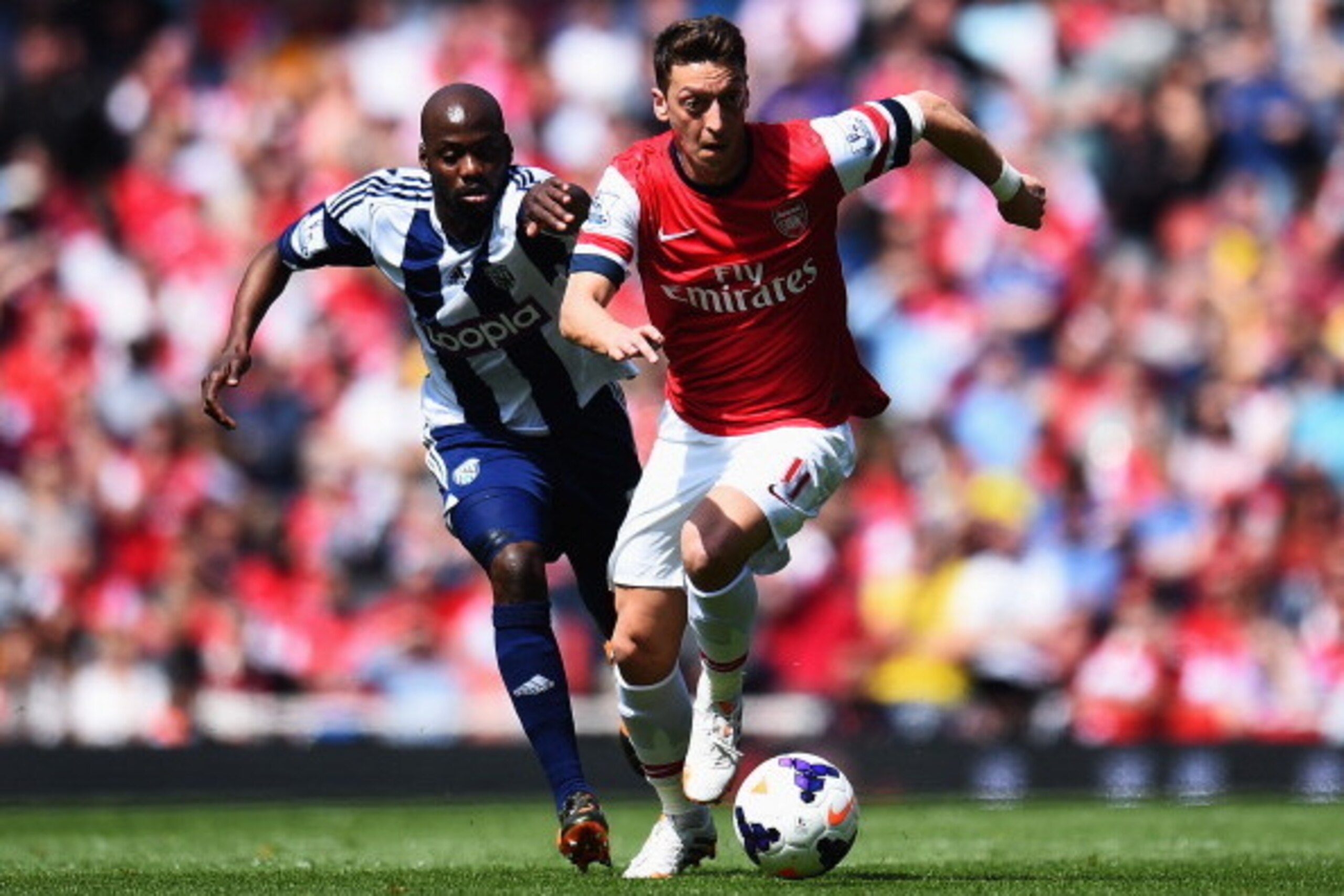 LONDON, ENGLAND - MAY 04: Mesut Ozil (R) of Arsenal holds off the challenge of Youssuf Mulumbu (L) of West Bromwich Albion during the Barclays Premier League match between Arsenal and West Bromwich Albion at the Emirates Stadium on May 4, 2014 in London, LONDON, ENGLAND - MAY 04: Mesut Ozil (R) of Arsenal holds off the challenge of Youssuf Mulumbu (L) of West Bromwich Albion during the Barclays Premier League match between Arsenal and West Bromwich Albion at the Emirates Stadium on May 4, 2014 in London,