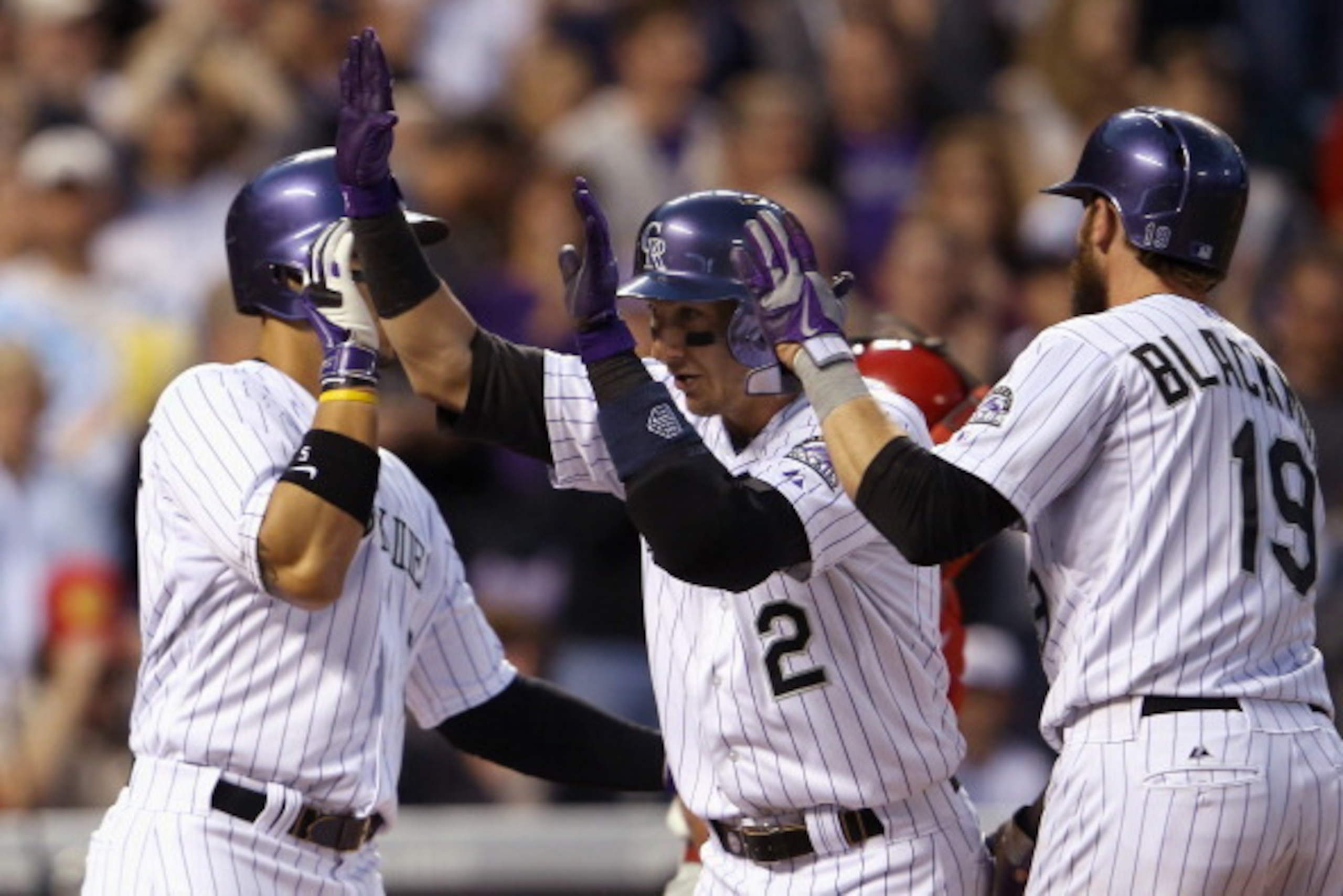 DENVER, CO - APRIL 18:  Troy Tulowitzki #2 of the Colorado Rockies is welcomed home by Charlie Blackmon #19 and Carlos Gonzalez #5 of the Rockies after they scored on Tuloitzki's three run home run off of starting pitcher Jonathan Pettibone #44 of the Phi