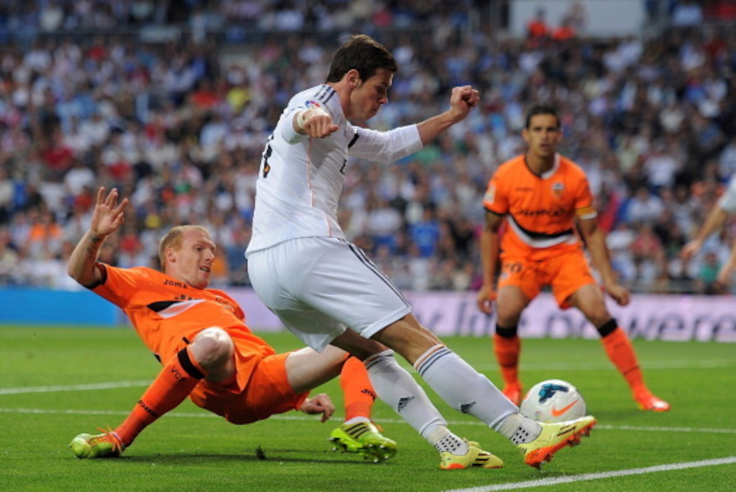 MADRID, SPAIN - MAY 04: Gareth Bale of Real Madrid FC crosses the ball beside  Jeremy Mathieu of Valencia CF during the La Liga match between Real Madrid CF and Valencia CF at Santiago Bernabeu stadium on May 4, 2014 in Madrid, Spain.  (Photo by Denis Doy