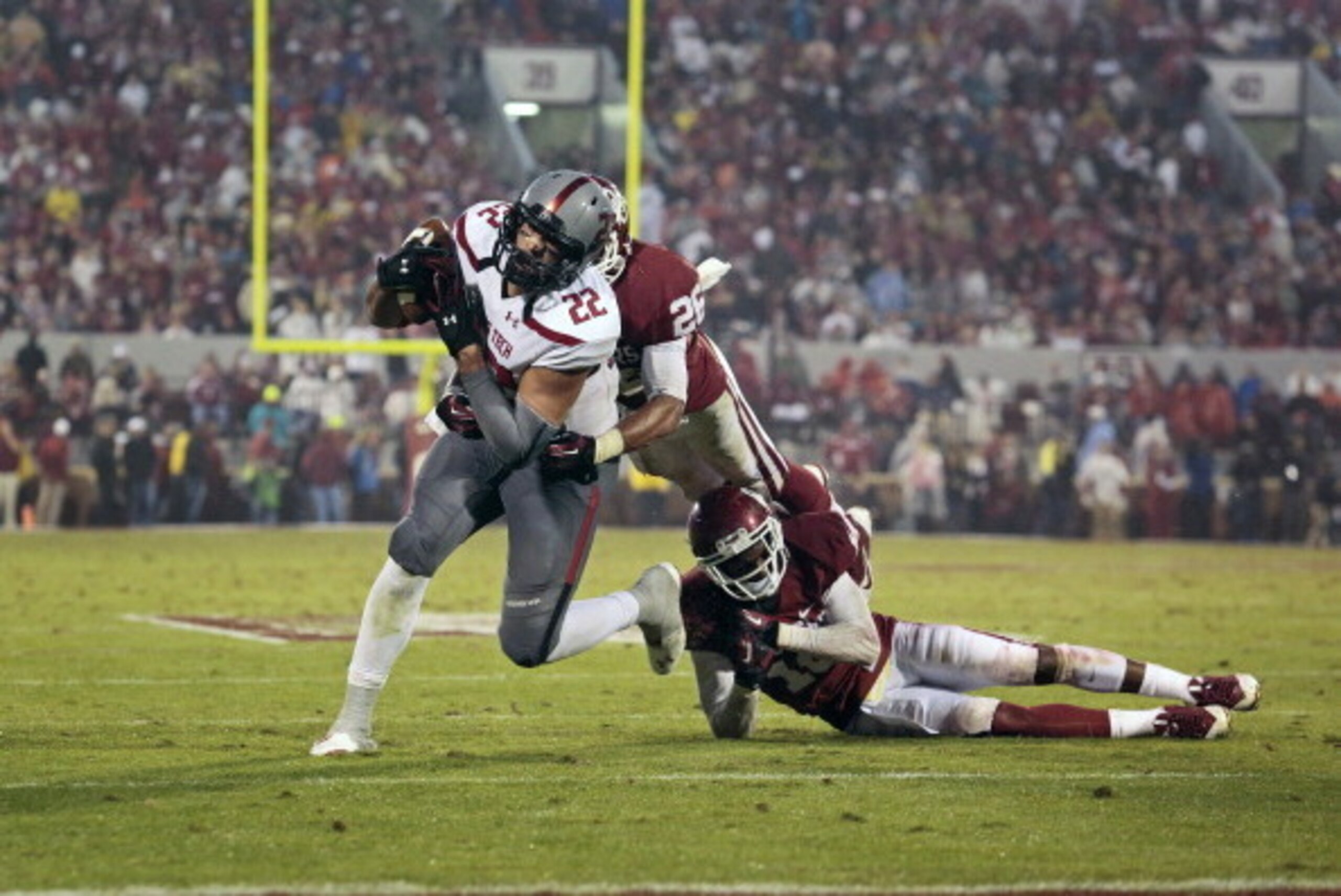 NORMAN, OK - OCTOBER 26:  Linebacker Jordan Evans #26 and defensive back Quentin Hayes #10 of the Oklahoma Sooners try to take down tight end Jace Amaro #22 of the Texas Tech Red Raiders October 26, 2013 at Gaylord Family-Oklahoma Memorial Stadium in Norm