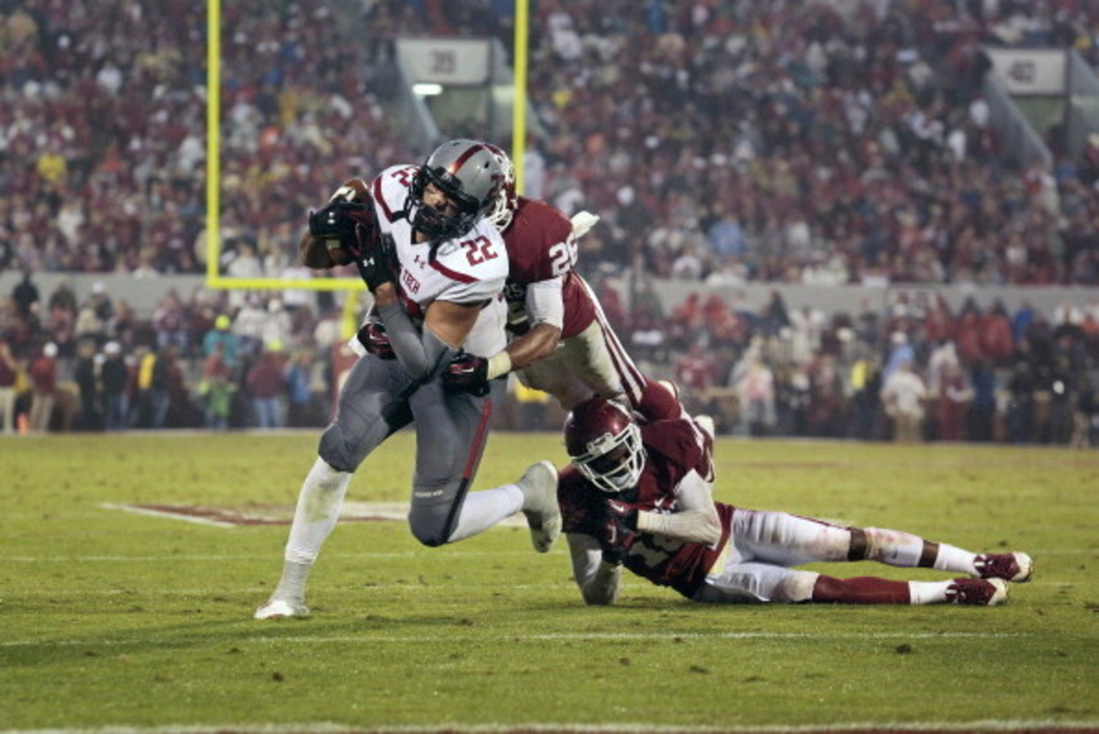 NORMAN, OK - OCTOBER 26:  Linebacker Jordan Evans #26 and defensive back Quentin Hayes #10 of the Oklahoma Sooners try to take down tight end Jace Amaro #22 of the Texas Tech Red Raiders October 26, 2013 at Gaylord Family-Oklahoma Memorial Stadium in Norm