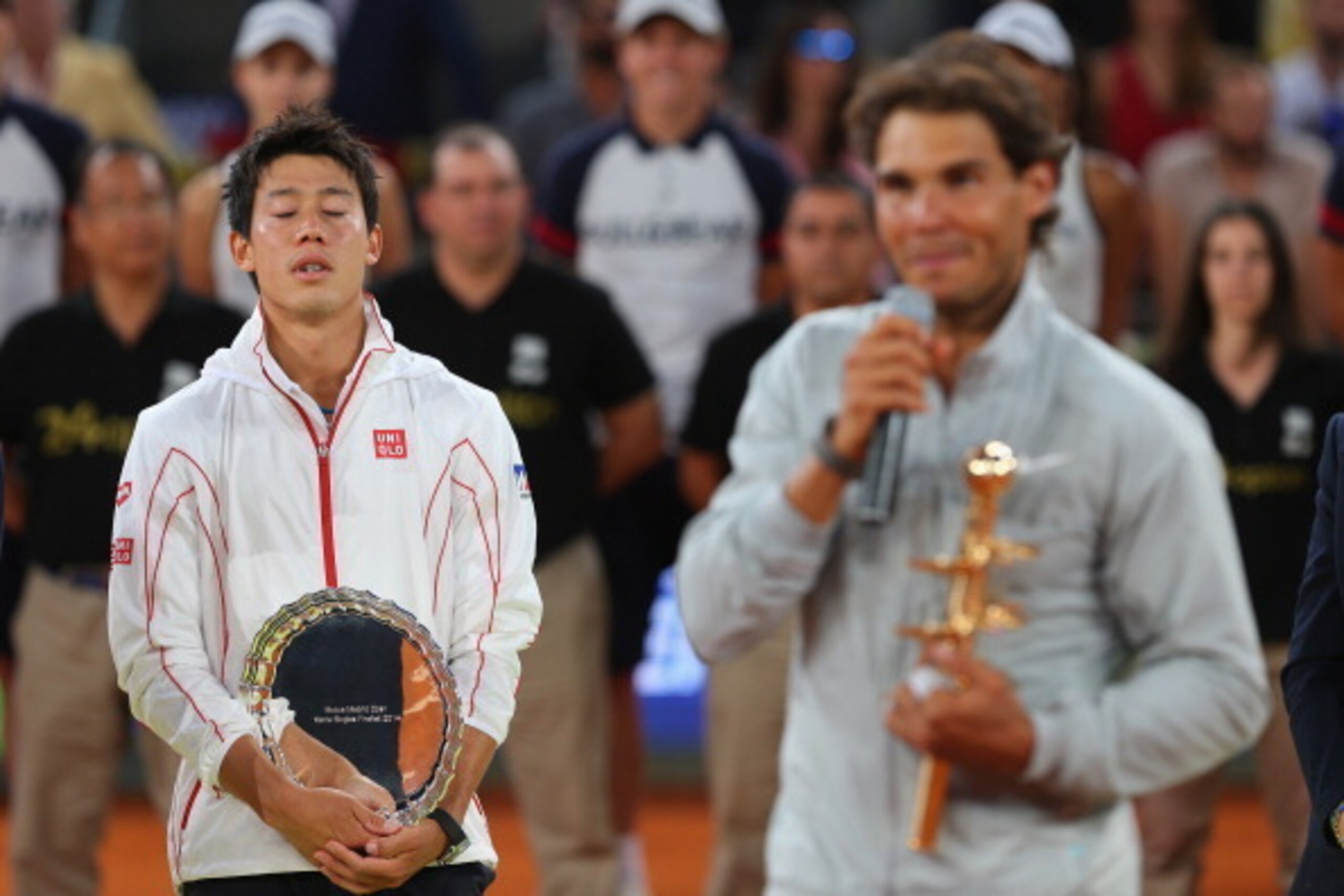 MADRID, SPAIN - MAY 11:  Rafael Nadal of Spain makes his victory speach as Kei Nishikori of Japan shows his dejection after he retired injured in the third set in their final match during day nine of the Mutua Madrid Open tennis tournament at the Caja Mag