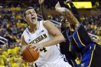 Nov 29, 2013; Ann Arbor, MI, USA; Michigan Wolverines forward Mitch McGary (4) is defended by Coppin State Eagles forward Zach Burnham in the second half at Crisler Arena. Michigan won 87-45. Mandatory Credit: Rick Osentoski-USA TODAY Sports