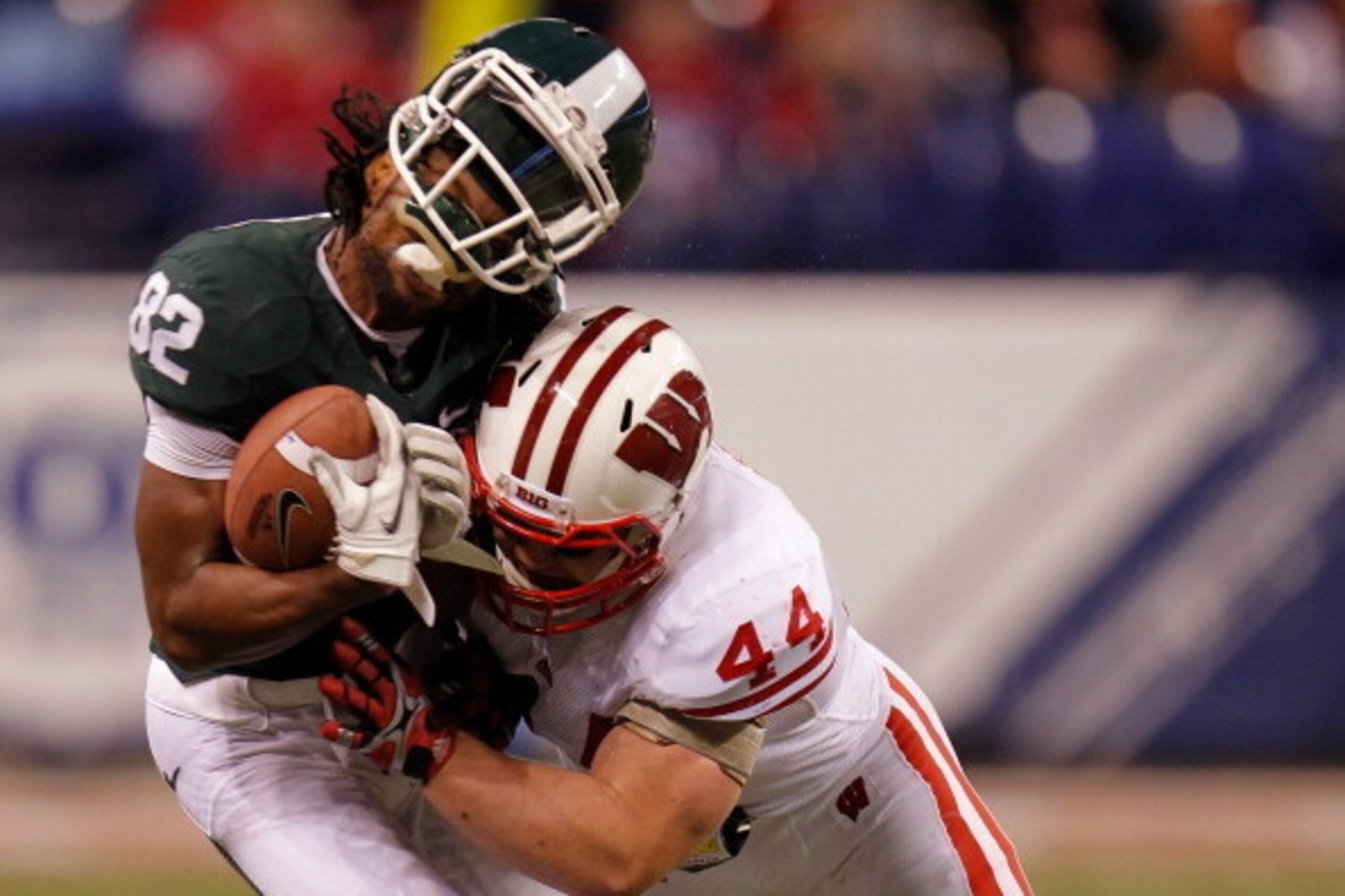 INDIANAPOLIS, IN - DECEMBER 03:  Keshawn Martin #82 of the Michigan State Spartans loses his helmet as he is hit by Chris Borland #44 of the Wisconsin Badgers during the third quarter of the Big 10 Conference Championship Game at Lucas Oil Stadium on Dece