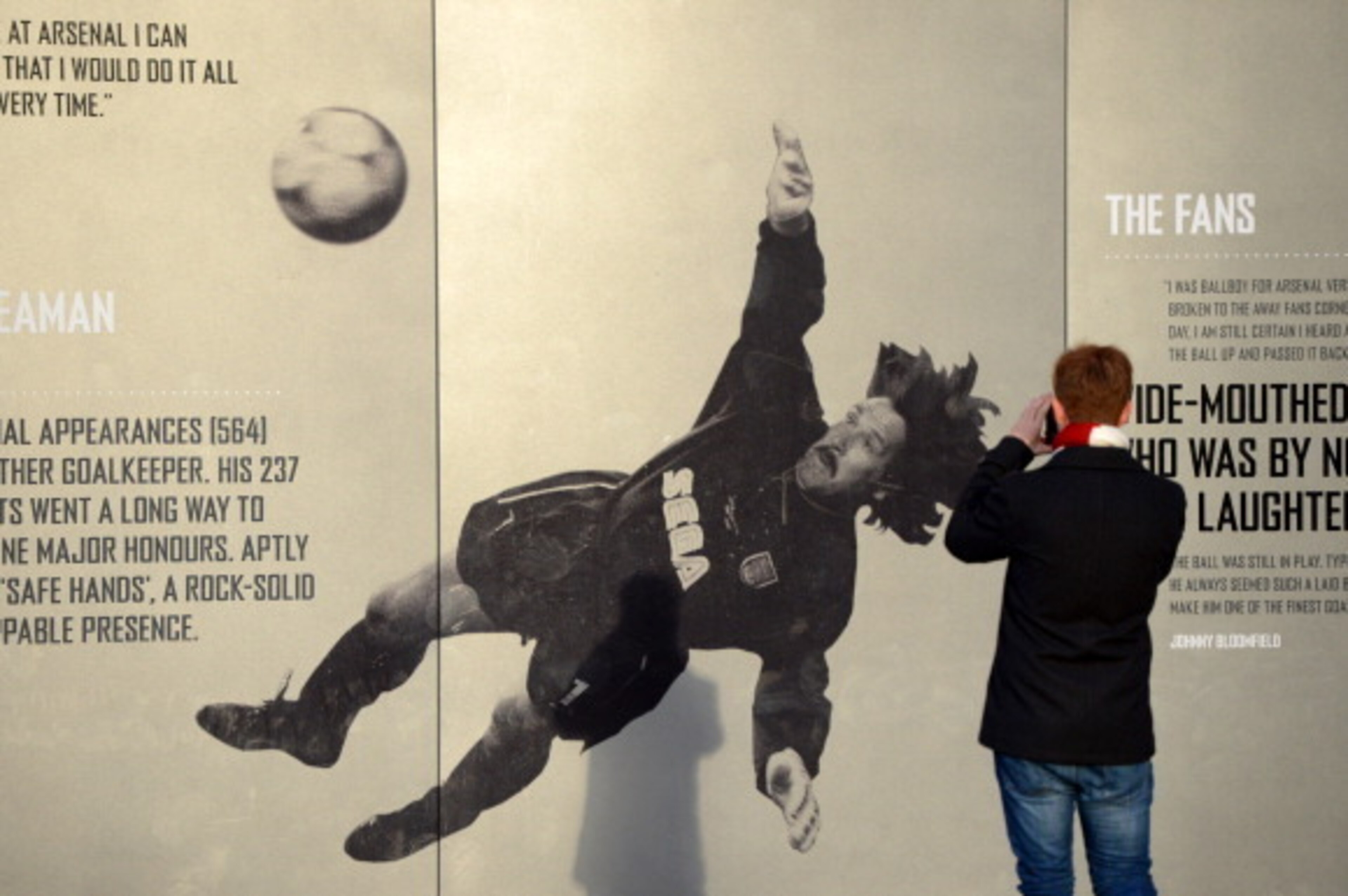 LONDON, ENGLAND - DECEMBER 08: An Arsenal fan takes a photo of a picture of former Arsenal goalkeeper David Seaman ahead of the Barclays Premier League match between Arsenal and Everton at Emirates Stadium on December 8, 2013 in London, England.  (Photo b