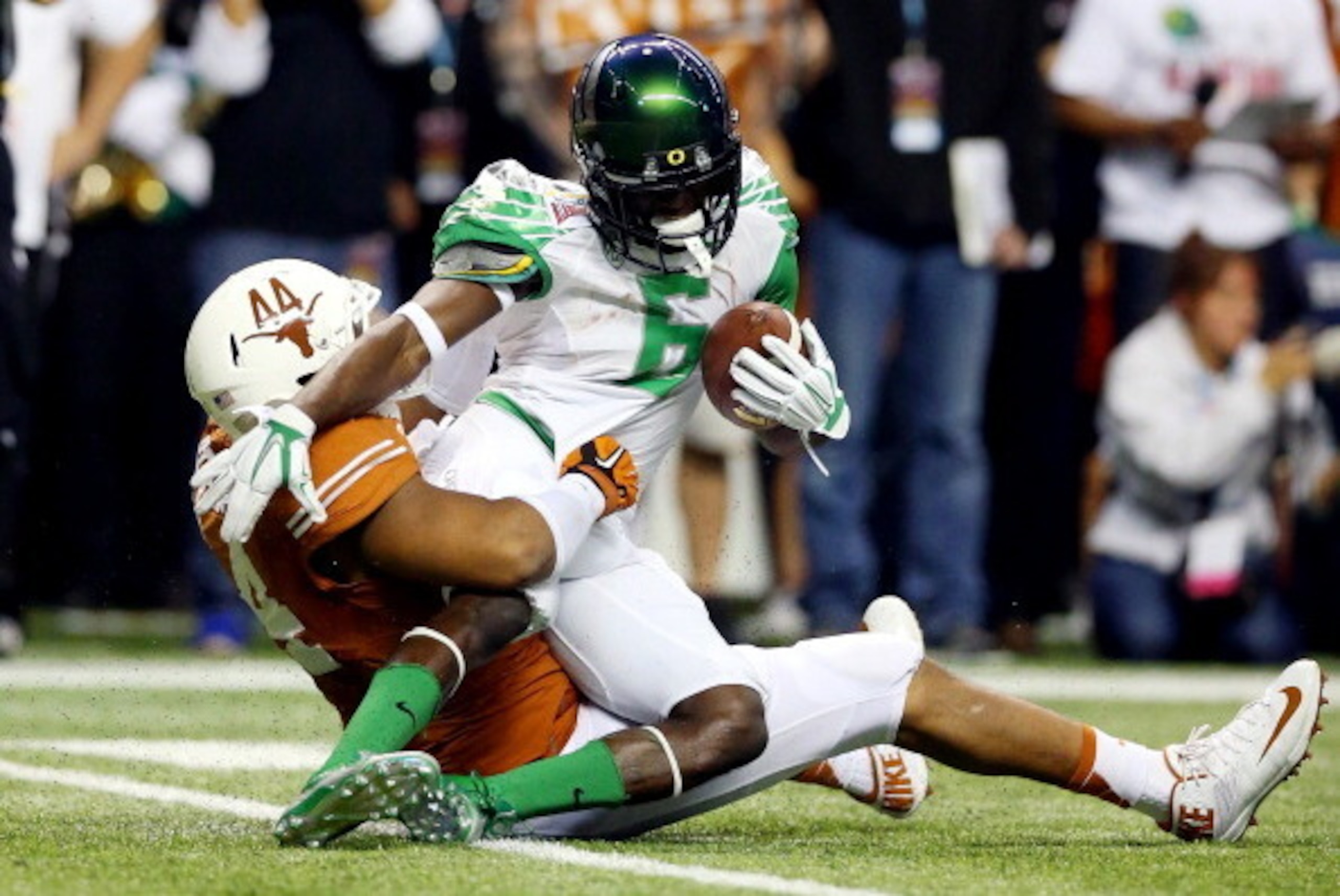 SAN ANTONIO, TX - DECEMBER 30: Running back De'Anthony Thomas #6 of the Oregon Ducks is tackled by defensive end Jackson Jeffcoat #44 of the Texas Longhorns in the second quarter of the Valero Alamo Bowl at the Alamodome on December 30, 2013 in San Antoni
